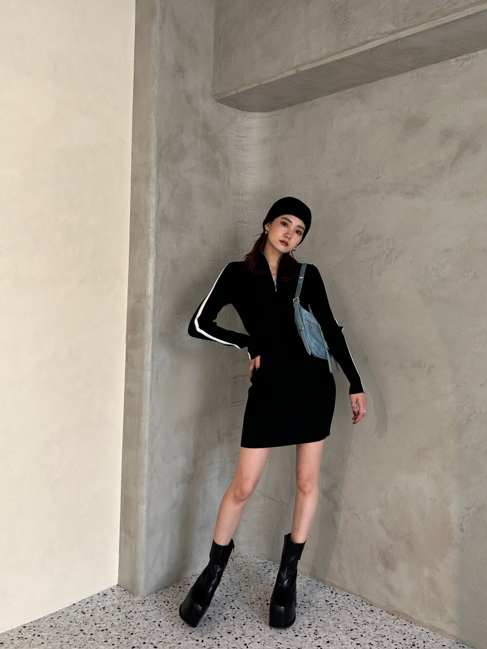 ブラック系のワンピース、ブラック系のブーツ、ブルー系のハンドバッグを着用したレディースの冬コーディネートの2枚目の写真