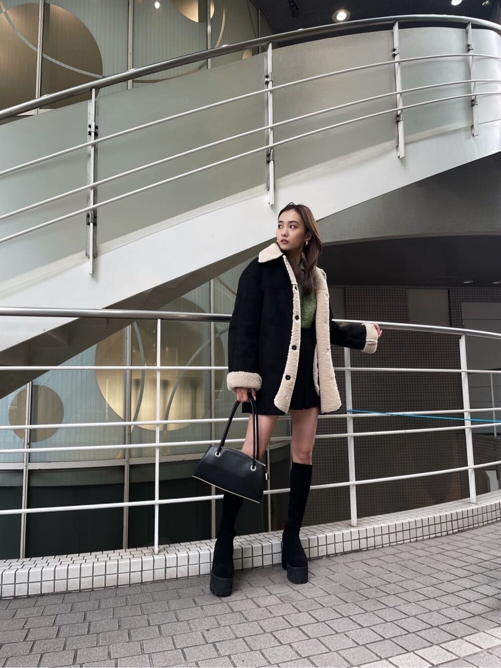 ブラック系のムートンコート、ブラック系のブーツを着用したレディースの秋コーディネートの3枚目の写真