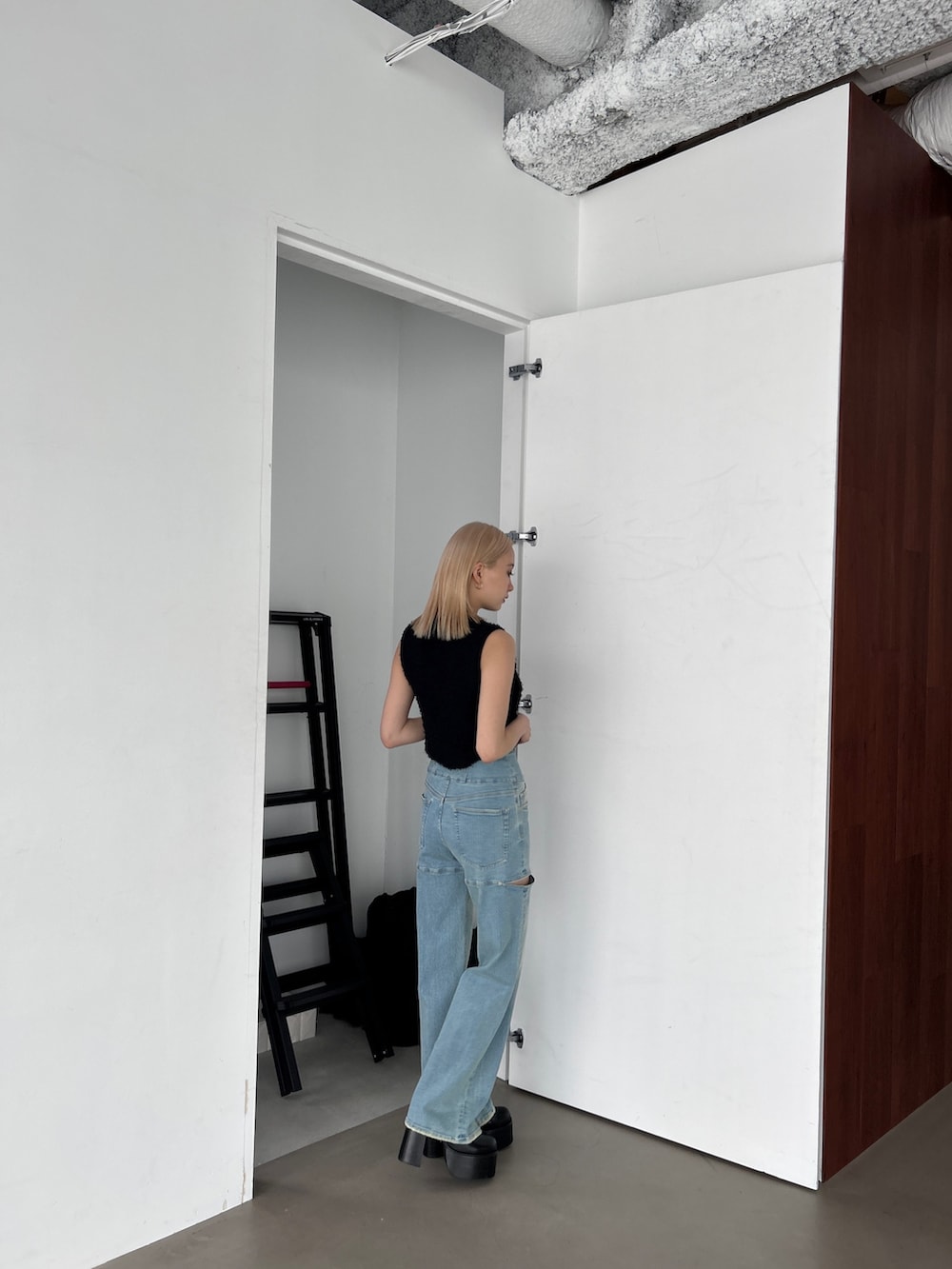 ブラック系のタンクトップ、ブルー系のデニムパンツを着用したレディースの夏コーディネートの5枚目の写真