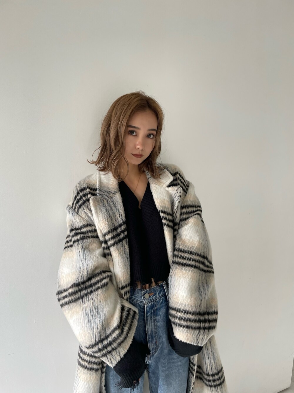 その他のチェスターコート、ブルー系のデニムパンツ、ブラック系のニット/セーターを着用したレディースの冬コーディネートの5枚目の写真