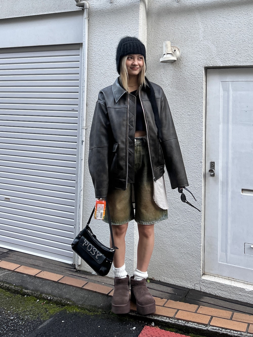 ブラック系のブルゾン、ブラウン系のデニムパンツ、ブラック系のハンドバッグを着用したレディースの冬コーディネートの2枚目の写真