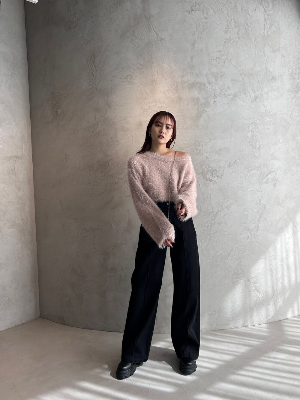 ブラック系のデニムパンツ、ピンク系のニット/セーター、ブラック系のスマホケース/カバーを着用したレディースの冬コーディネートの3枚目の写真