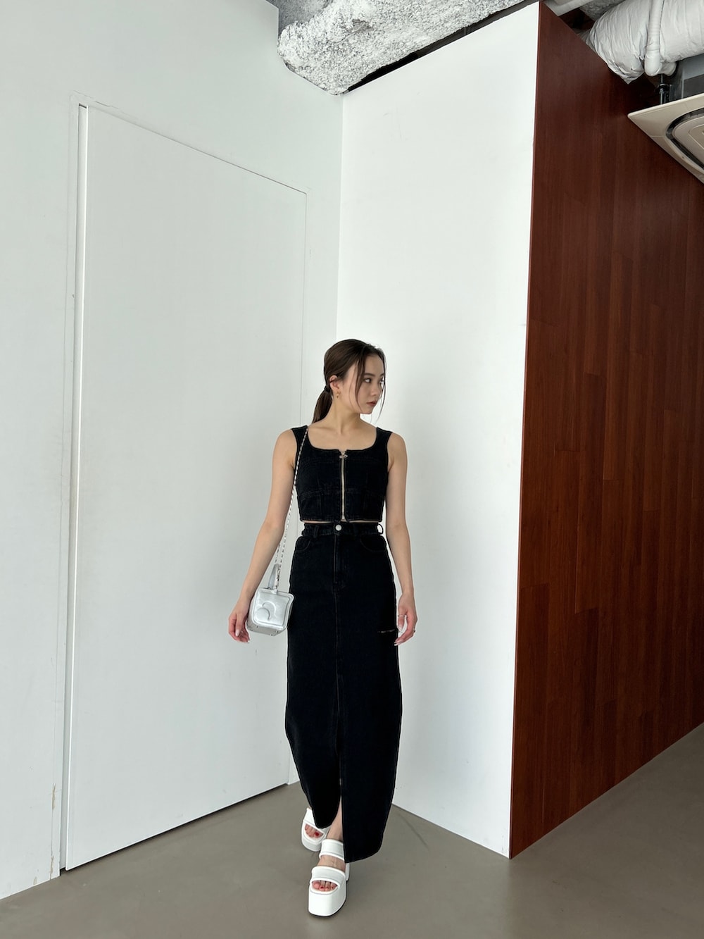 ブラック系のキャミソール、ブラック系のデニムスカート、ホワイト系のサンダルを着用したレディースの春コーディネートの2枚目の写真