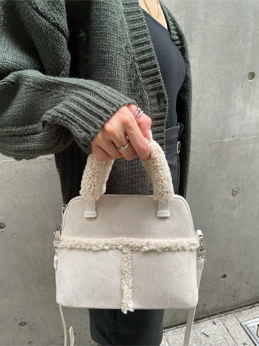 ホワイト系のハンドバッグ、ブラック系のハンドバッグ、グリーン系のニット/セーターを着用したレディースの秋コーディネートの3枚目の写真
