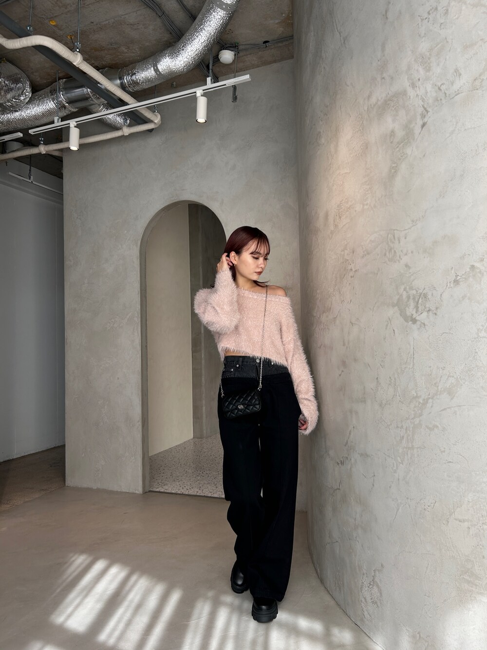 ブラック系のデニムパンツ、ピンク系のニット/セーター、ブラック系のスマホケース/カバーを着用したレディースの冬コーディネートの2枚目の写真