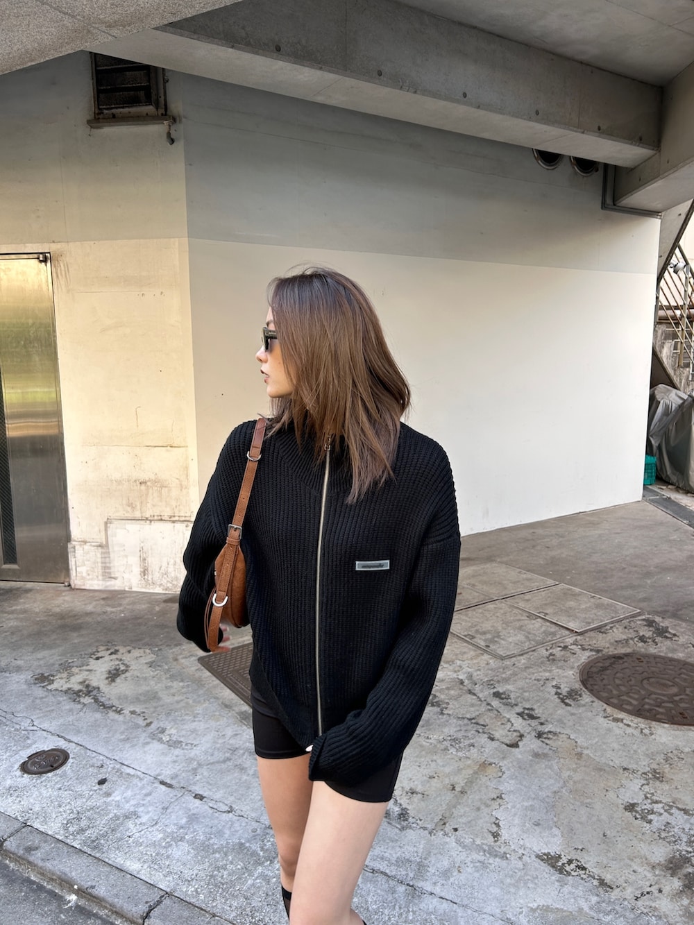 ブラック系のニット/セーター、ブラウン系のハンドバッグを着用したレディースの冬コーディネートの2枚目の写真