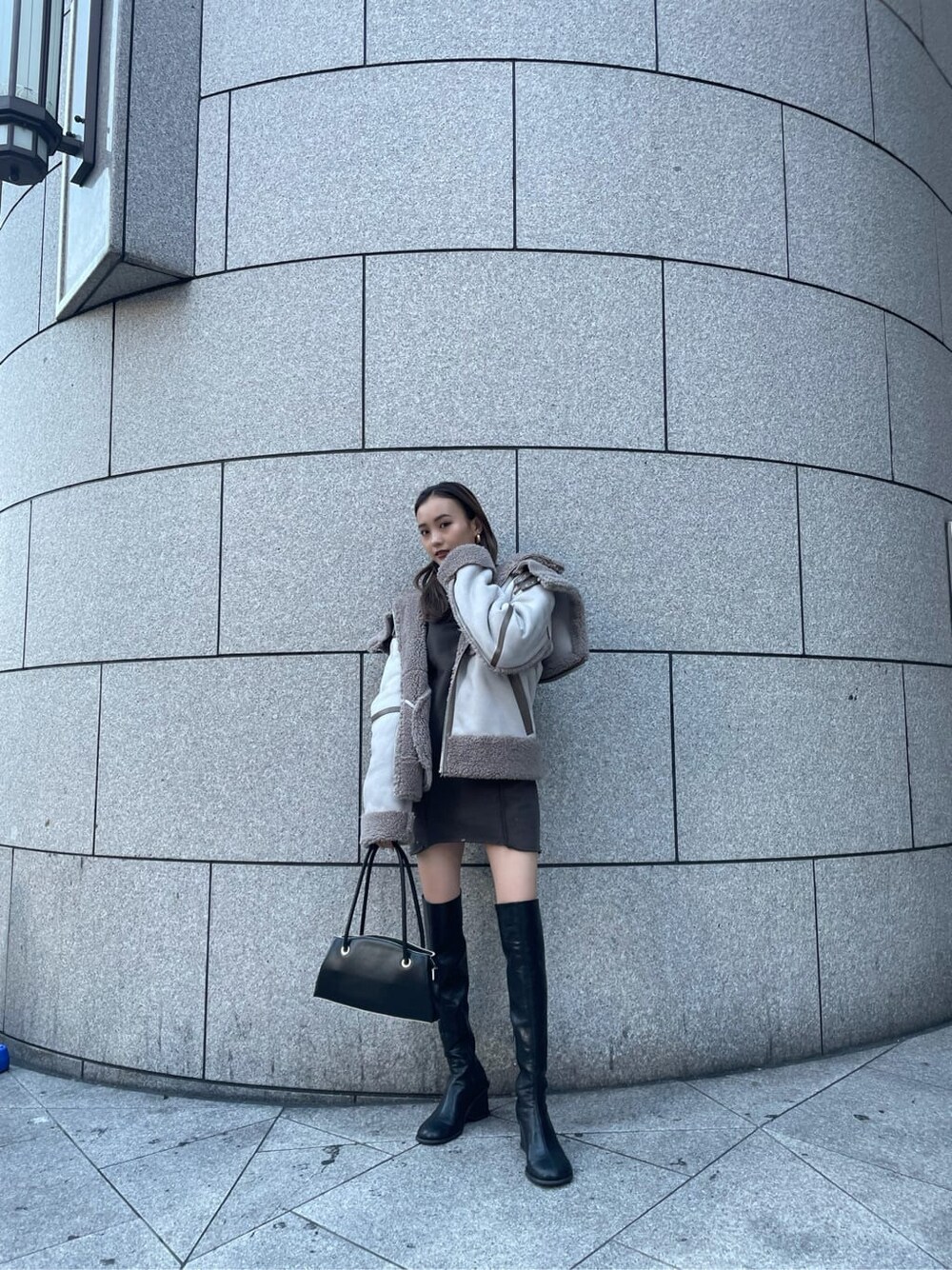 グレー系のムートンコート、ブラック系のブーツを着用したレディースの冬コーディネートの3枚目の写真