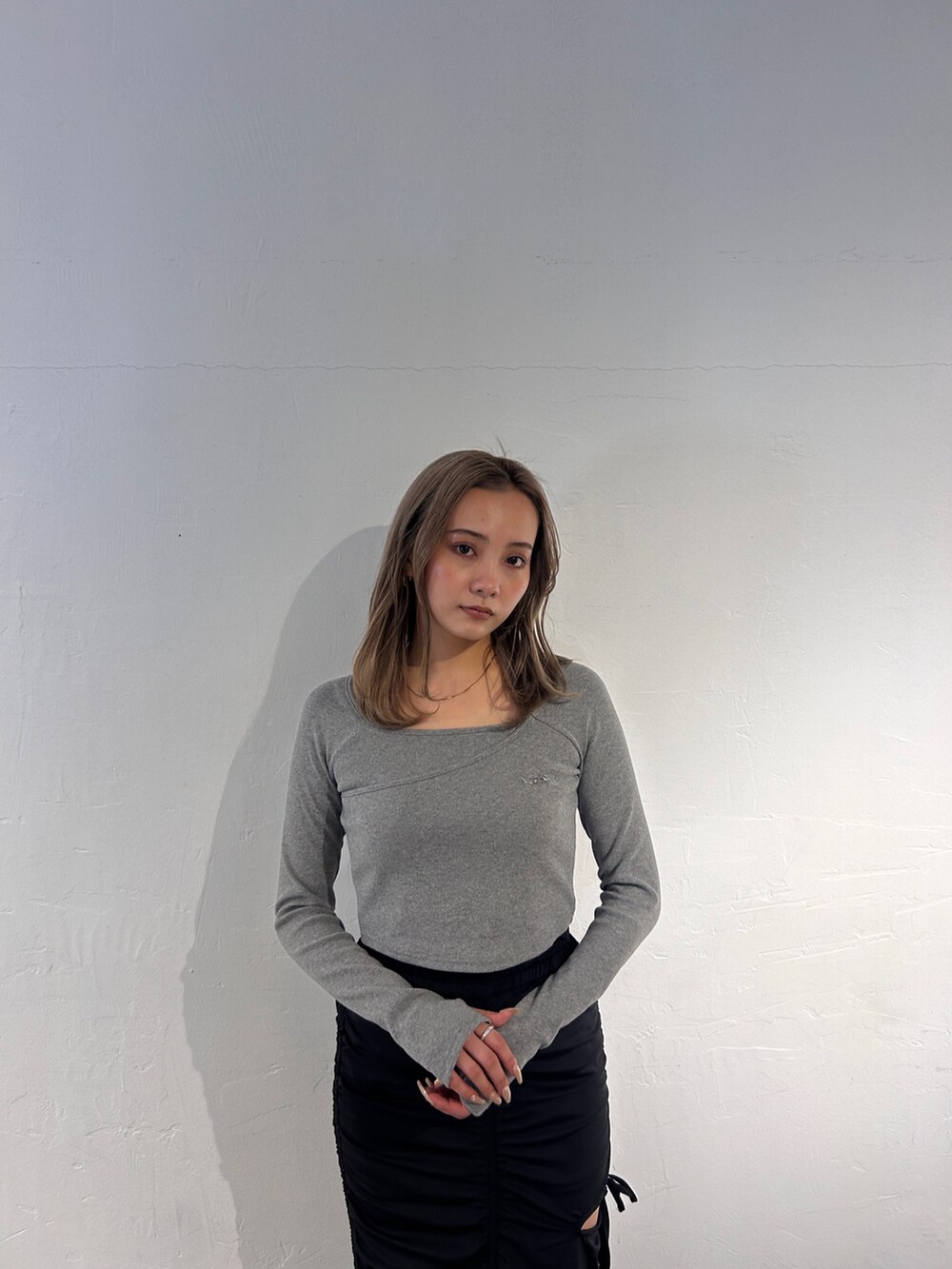 グレー系のTシャツ/カットソー、ブラック系のスカート、ブラック系のブーツを着用したレディースの冬コーディネートの4枚目の写真