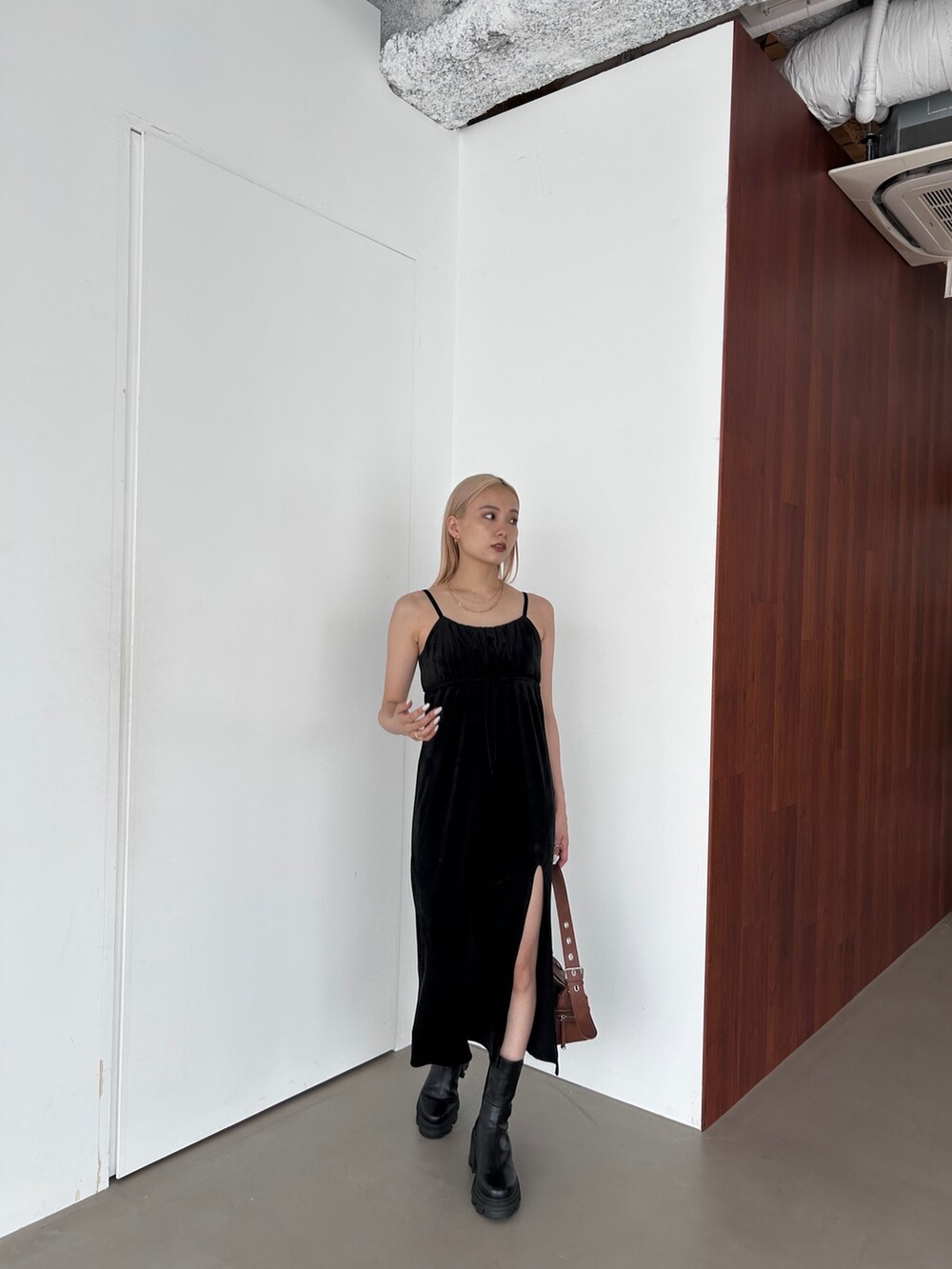 ブラック系のワンピース、ブラウン系のショルダーバッグ、ブラック系のブーツを着用したレディースの夏コーディネートの2枚目の写真