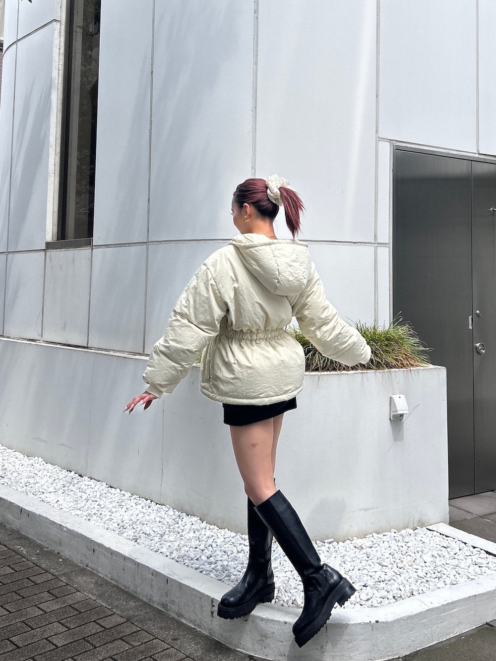 ホワイト系のブルゾン、ブラック系のブーツを着用したレディースの冬コーディネートの2枚目の写真