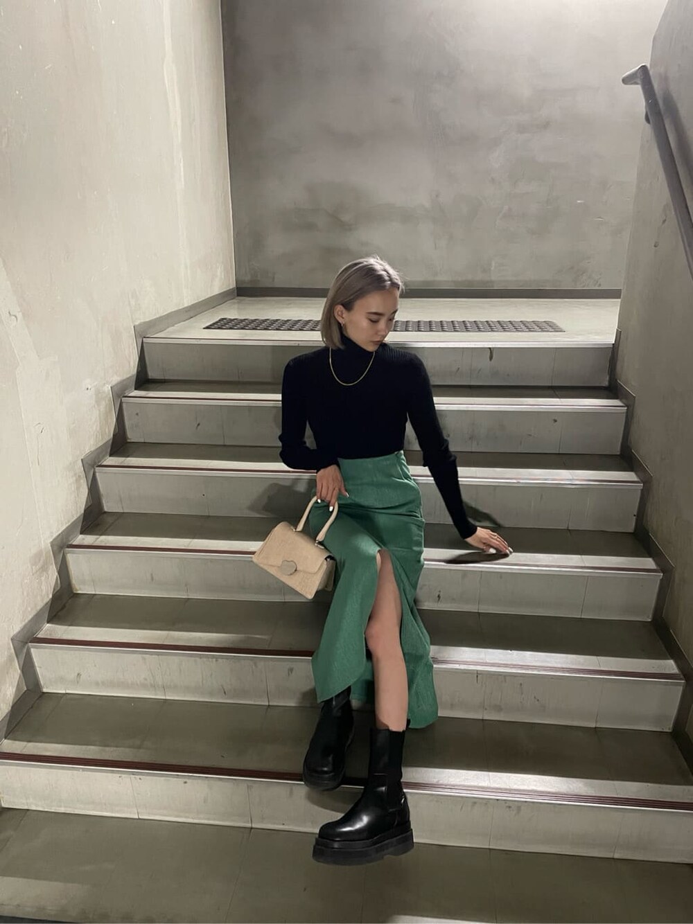 グリーン系のスカート、ブラック系のニット/セーターを着用したレディースの冬コーディネートの2枚目の写真