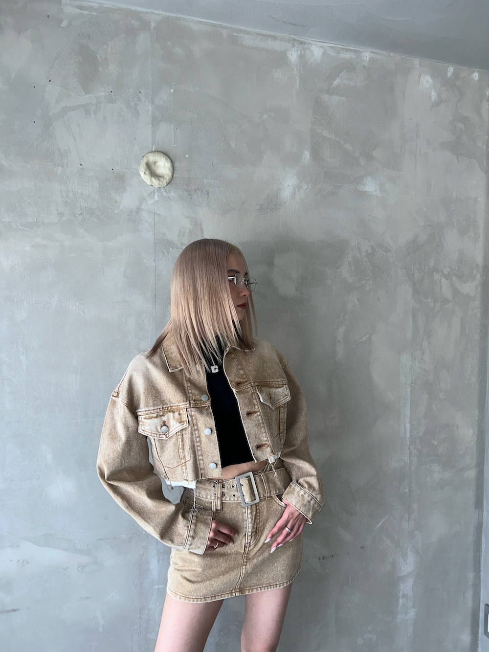 ベージュ系のデニムスカート、ベージュ系のデニムジャケット、ブラック系のブーツを着用したレディースの夏コーディネートの3枚目の写真