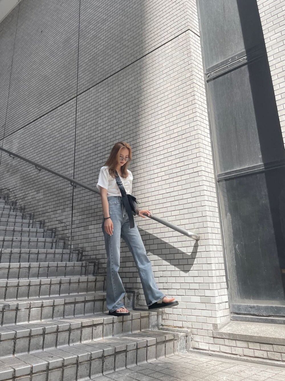 ブルー系のデニムパンツ、ホワイト系のショルダーバッグ、ホワイト系のTシャツ/カットソーを着用したレディースの夏コーディネートの2枚目の写真