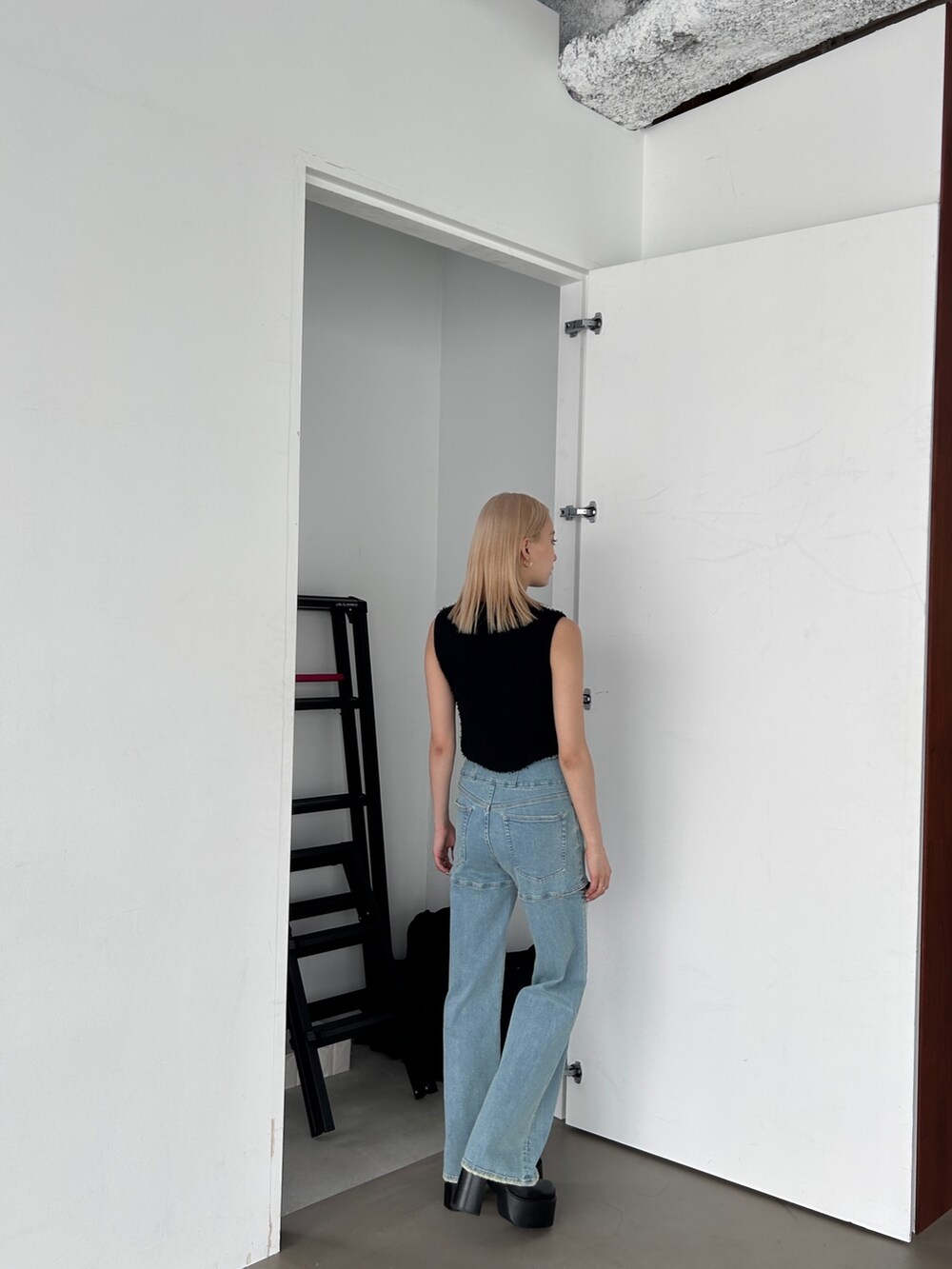 ブラック系のタンクトップ、ブルー系のデニムパンツを着用したレディースの夏コーディネートの6枚目の写真