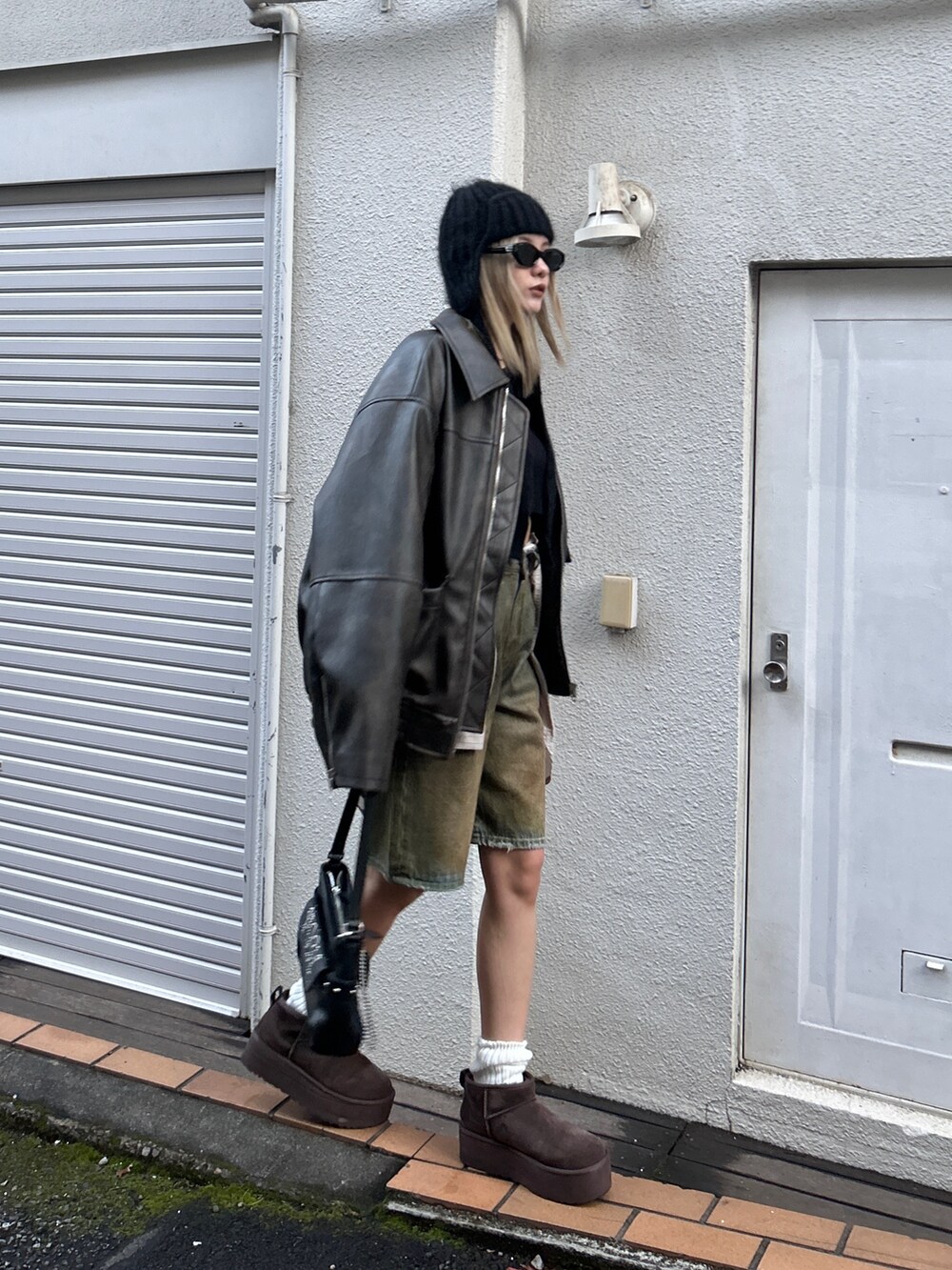 ブラック系のブルゾン、ブラウン系のデニムパンツ、ブラック系のハンドバッグを着用したレディースの冬コーディネートの2枚目の写真