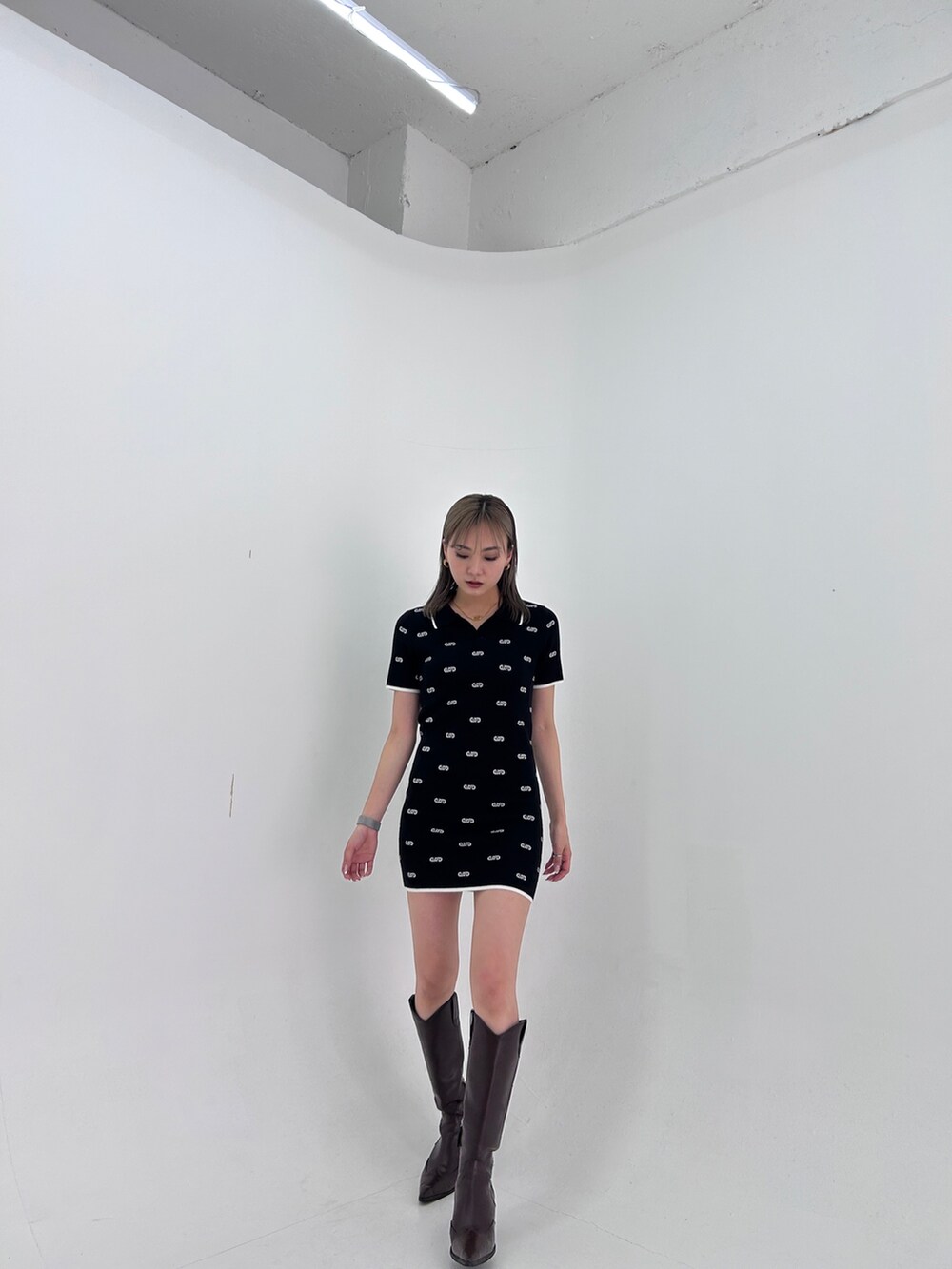 ブラック系のワンピース、ブラック系のブーツを着用したレディースの春コーディネートの2枚目の写真