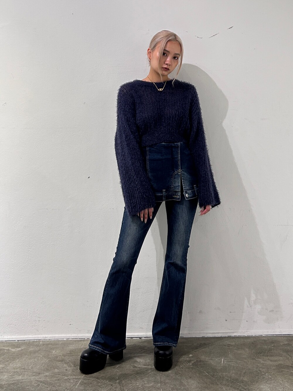 ブルー系のニット/セーター、ブルー系のデニムパンツ、ブラック系のブーツを着用したレディースの秋コーディネートの2枚目の写真