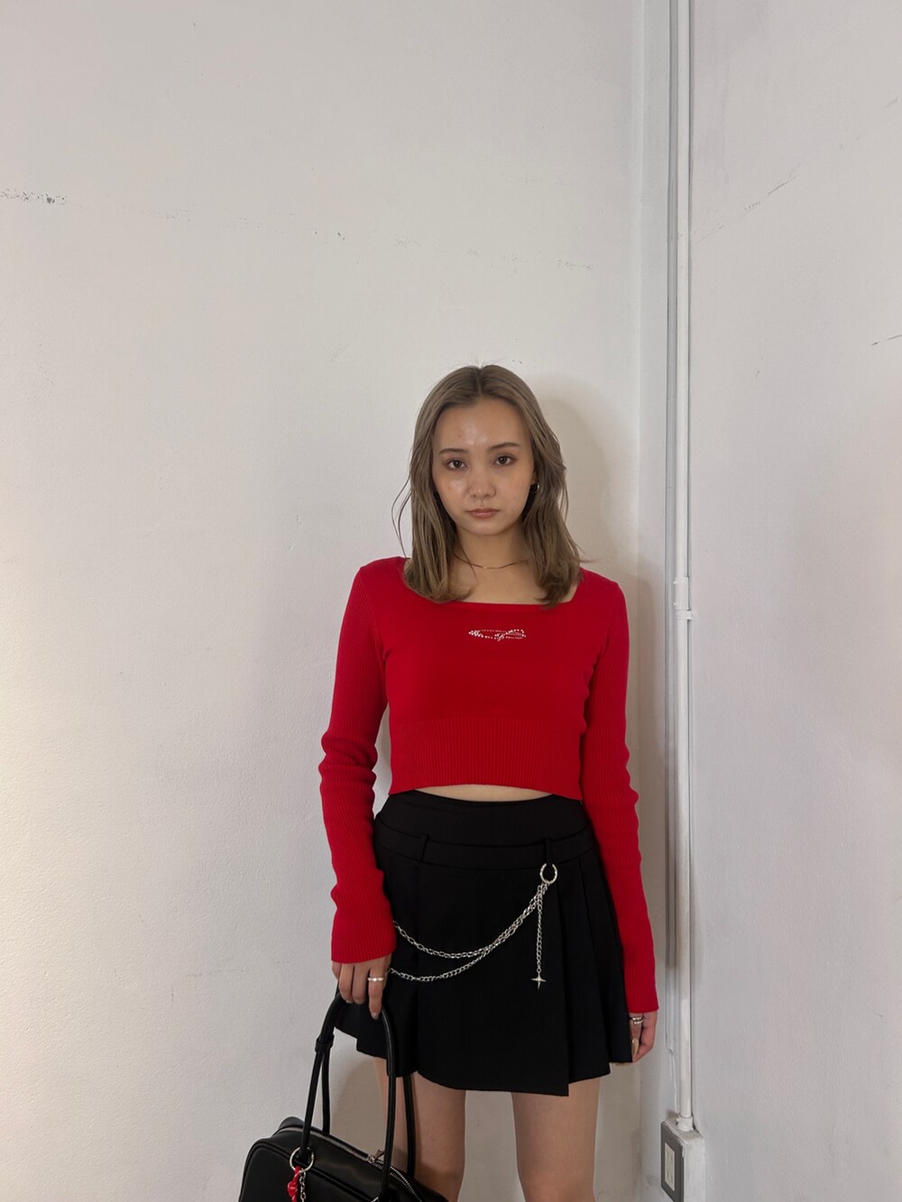 レッド系のニット/セーター、ブラック系のスカート、ブラック系のブーツを着用したレディースの冬コーディネートの4枚目の写真