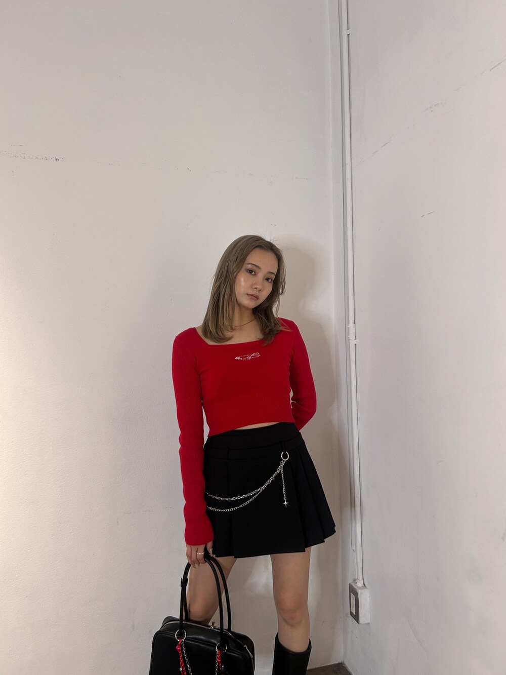 レッド系のニット/セーター、ブラック系のスカート、ブラック系のブーツを着用したレディースの冬コーディネートの3枚目の写真