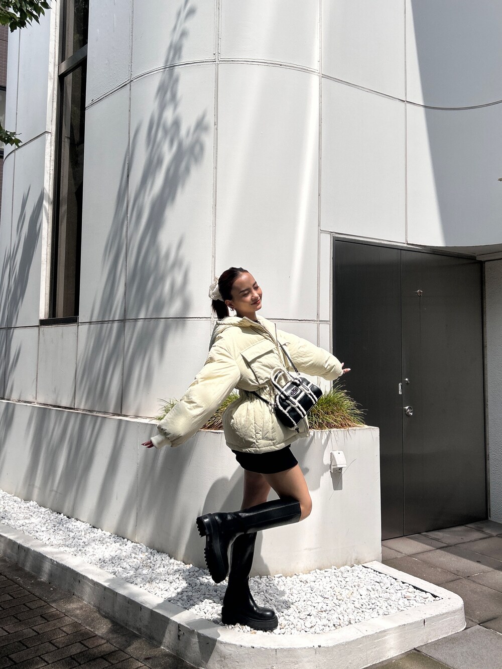 ホワイト系のブルゾン、ブラック系のブーツを着用したレディースの冬コーディネートの3枚目の写真