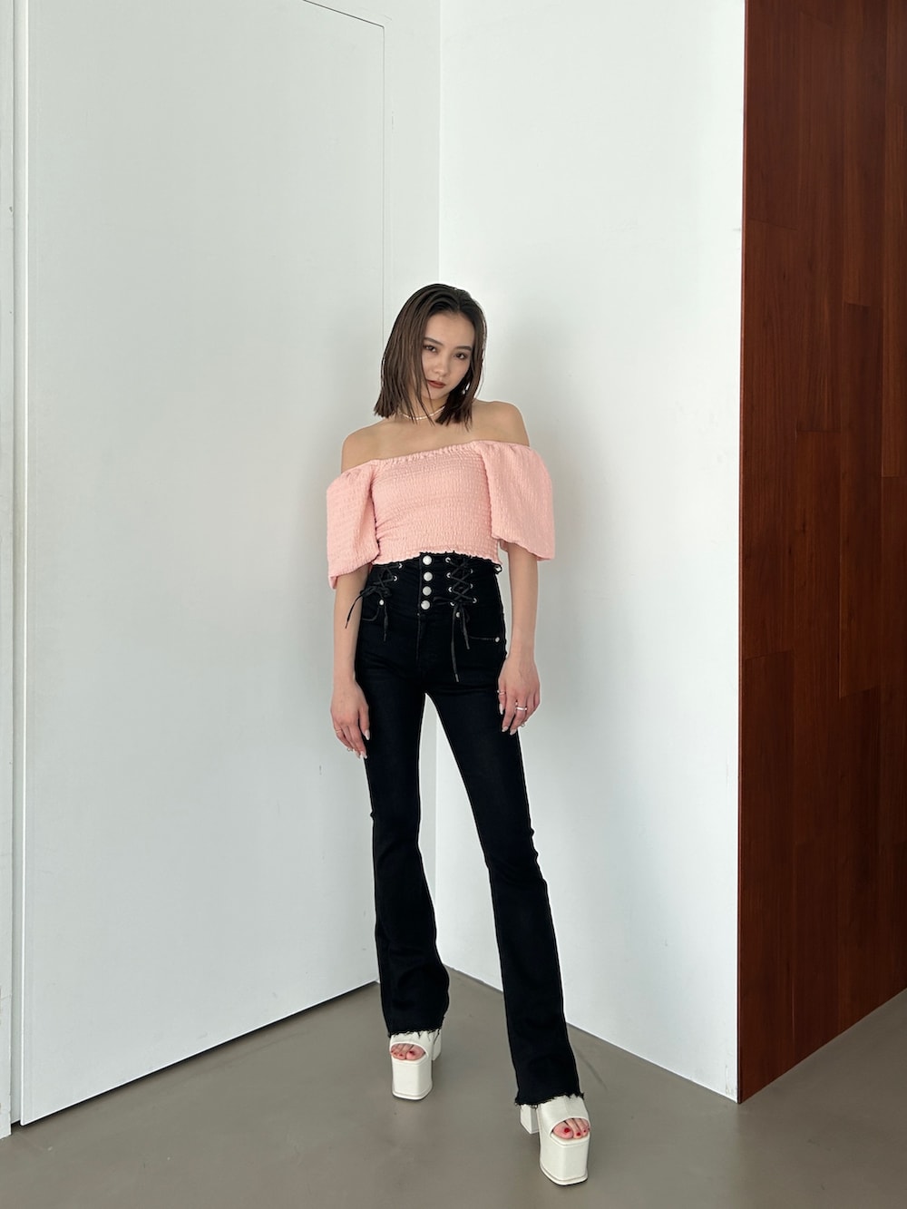 ピンク系のトップス、ブラック系のデニムパンツ、ホワイト系のサンダルを着用したレディースの春コーディネートの2枚目の写真