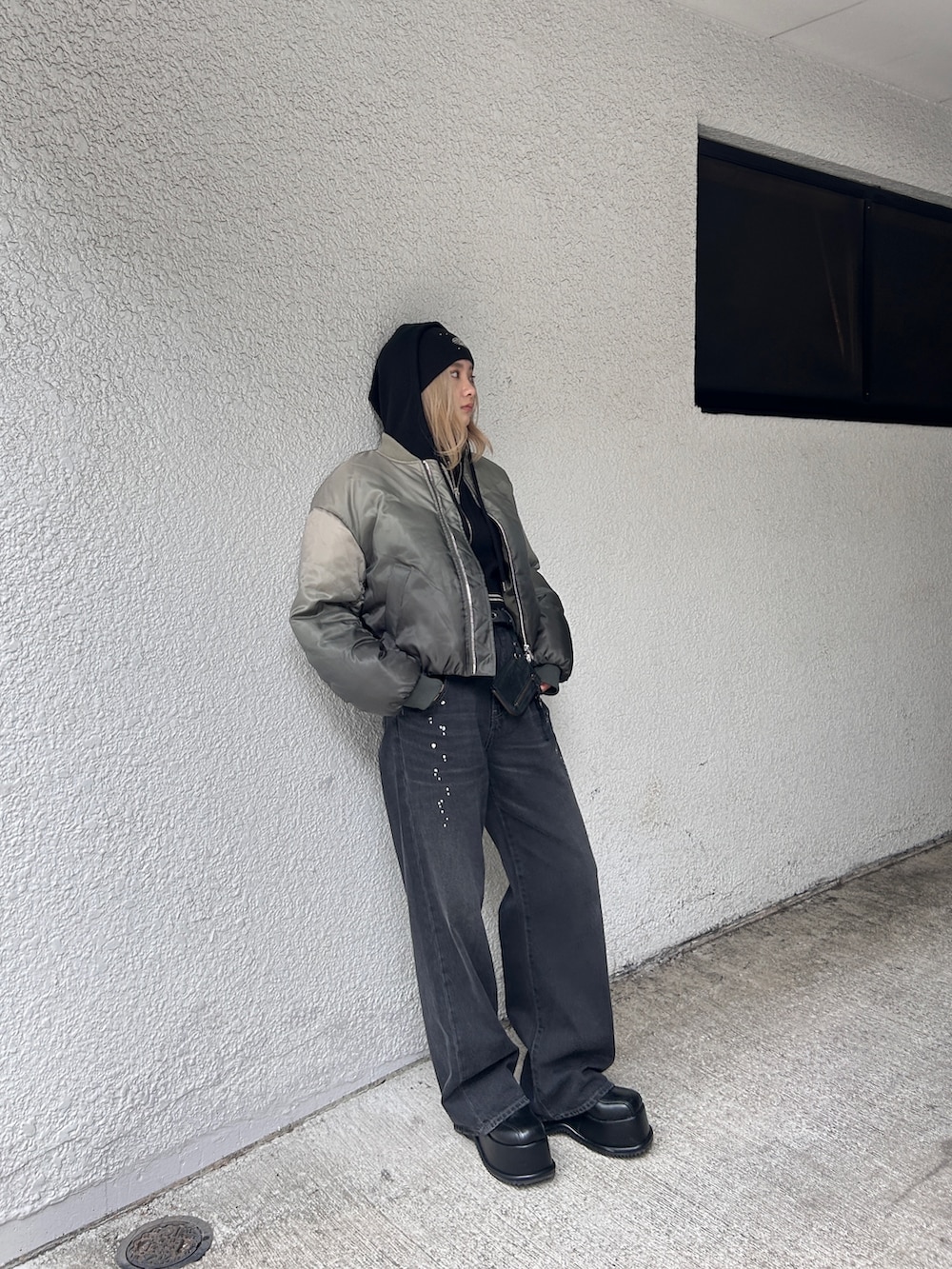 グレー系のブルゾン、ブラック系のデニムパンツ、ブラック系のローファーを着用したレディースの秋コーディネートの2枚目の写真