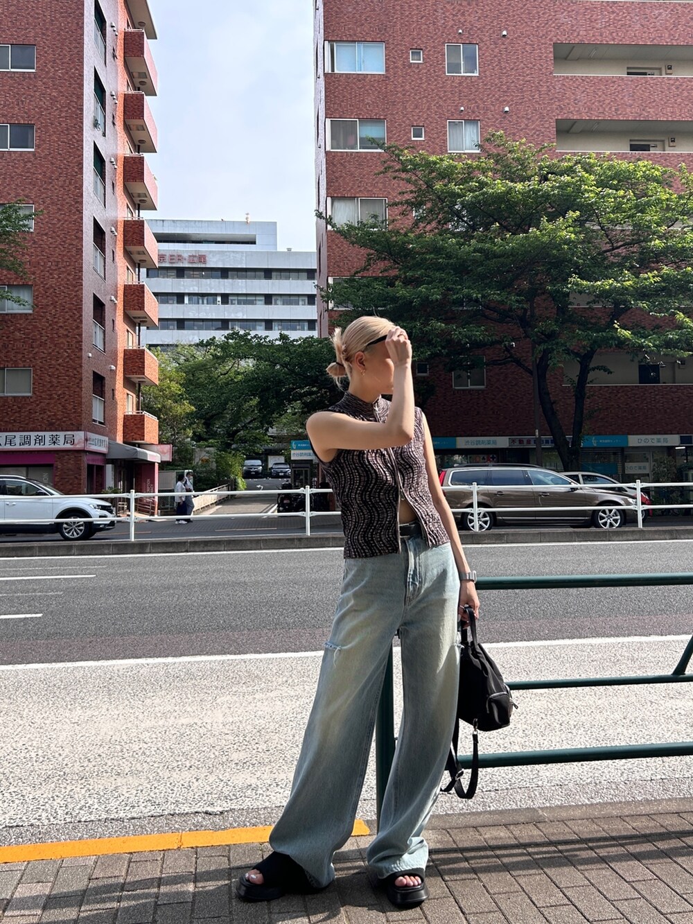 ブラウン系のタンクトップ、ブルー系のデニムパンツ、ブラック系のバッグを着用したレディースの春コーディネートの2枚目の写真