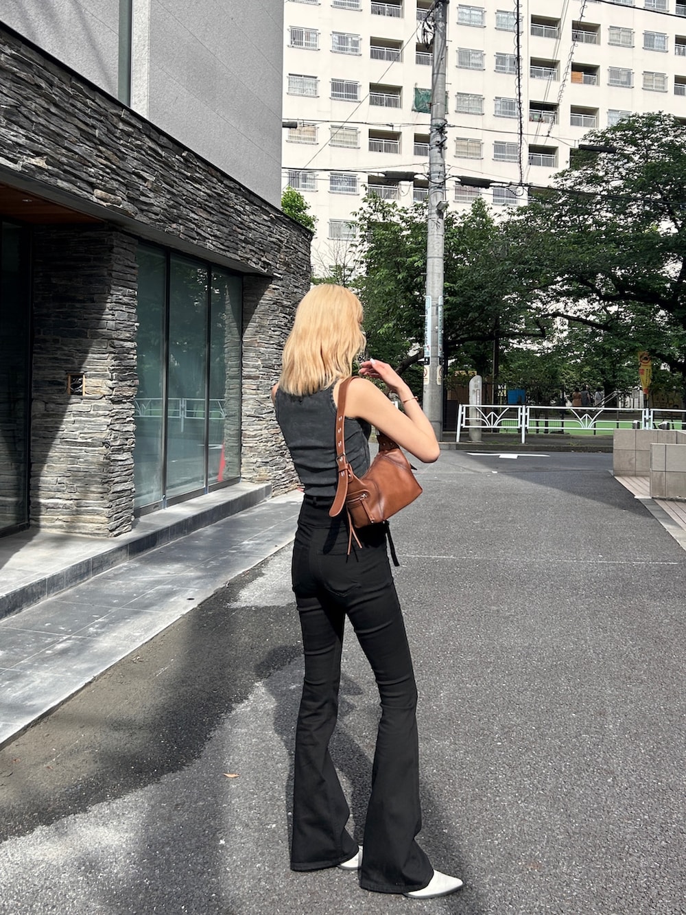 ブラック系のデニムパンツ、ブラック系のタンクトップ、ブラック系のブーツを着用したレディースの夏コーディネートの2枚目の写真