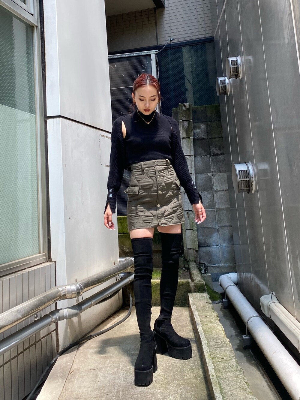 ブラック系のニット/セーター、グリーン系のスカート、ブラック系のブーツを着用したレディースの秋コーディネートの2枚目の写真
