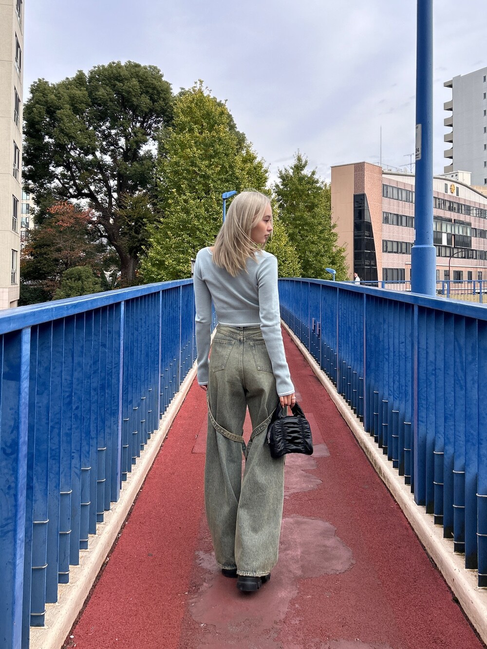 グレー系のニット/セーター、ホワイト系のデニムパンツ、ブラック系のハンドバッグを着用したレディースの冬コーディネートの4枚目の写真