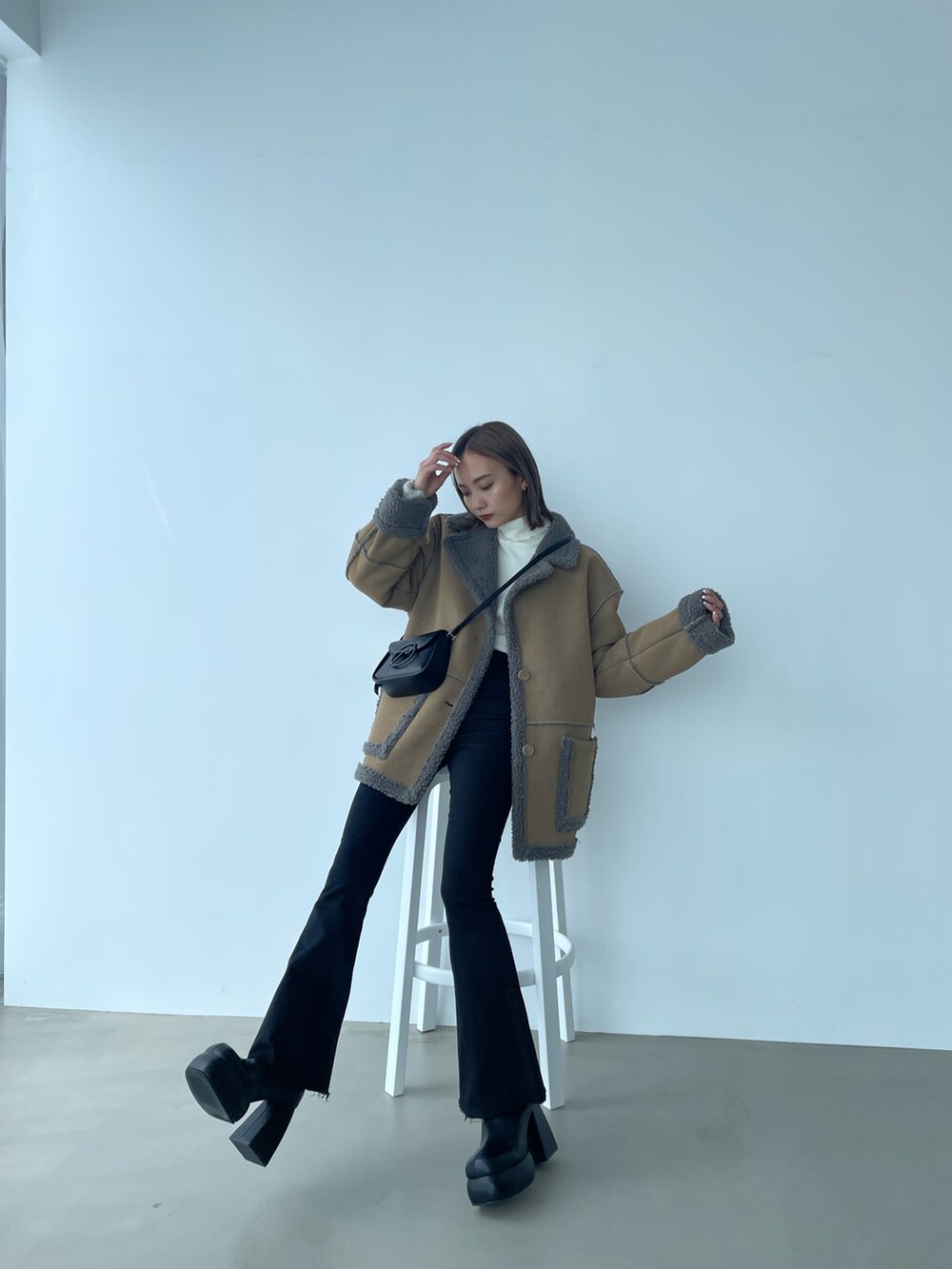 ベージュ系のムートンコートを着用したレディースの秋コーディネートの2枚目の写真