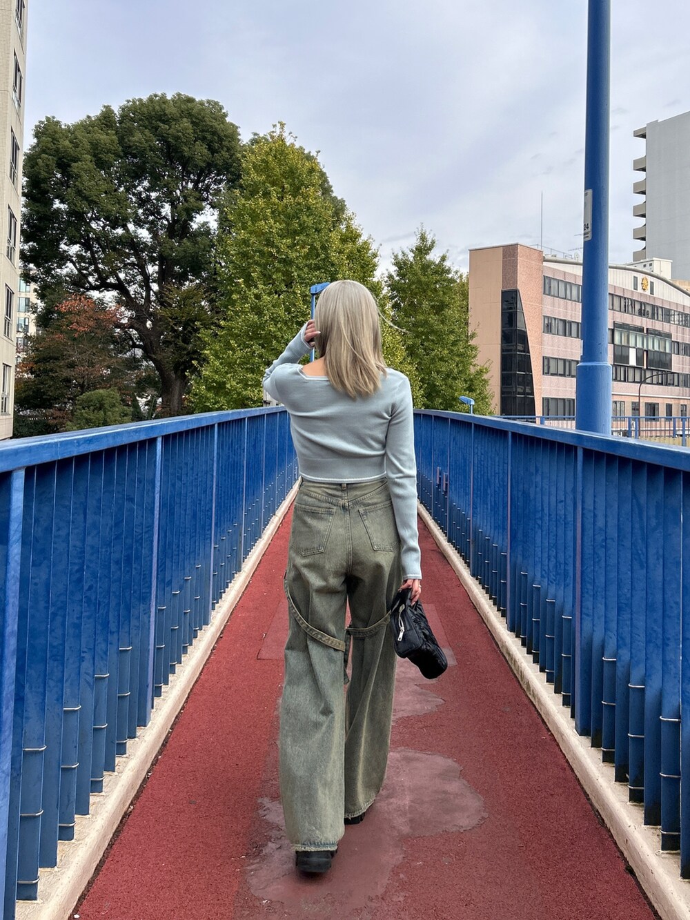 グレー系のニット/セーター、ホワイト系のデニムパンツ、ブラック系のハンドバッグを着用したレディースの冬コーディネートの3枚目の写真