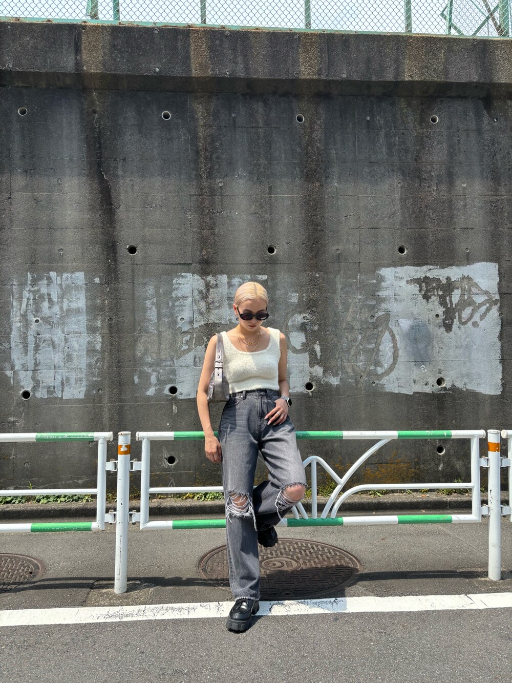 ホワイト系のニット/セーター、グレー系のデニムパンツ、シルバー系のハンドバッグを着用したレディースの夏コーディネートの2枚目の写真