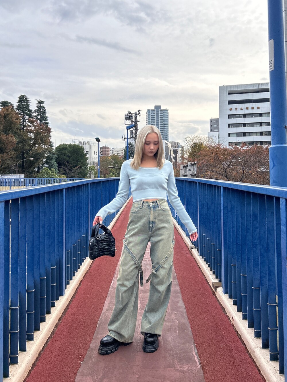 グレー系のニット/セーター、ホワイト系のデニムパンツ、ブラック系のハンドバッグを着用したレディースの冬コーディネートの2枚目の写真