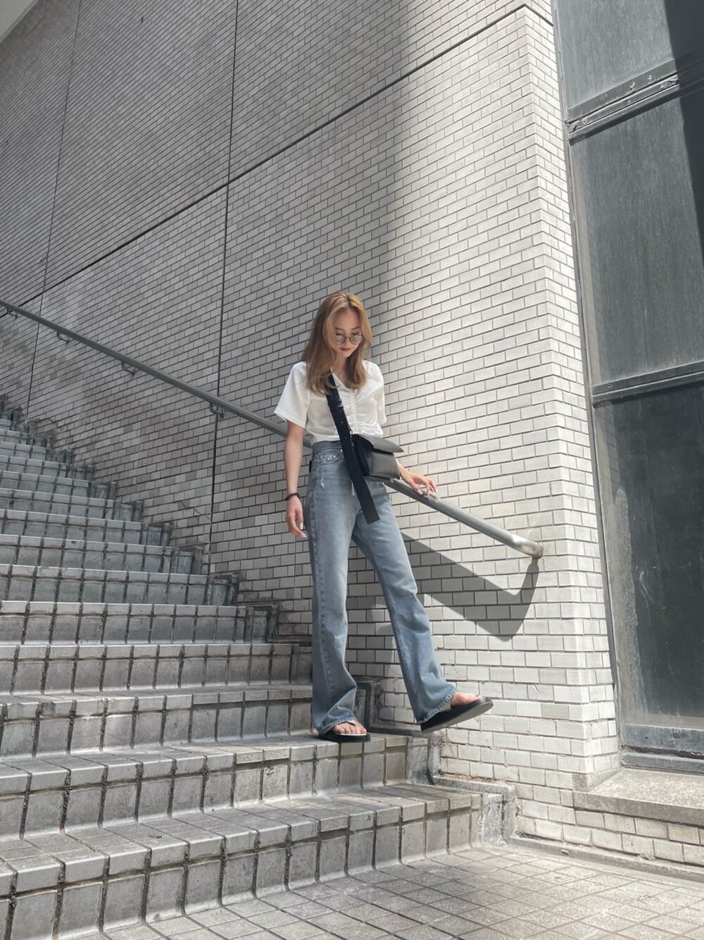 ブルー系のデニムパンツ、ホワイト系のショルダーバッグ、ホワイト系のTシャツ/カットソーを着用したレディースの夏コーディネートの3枚目の写真