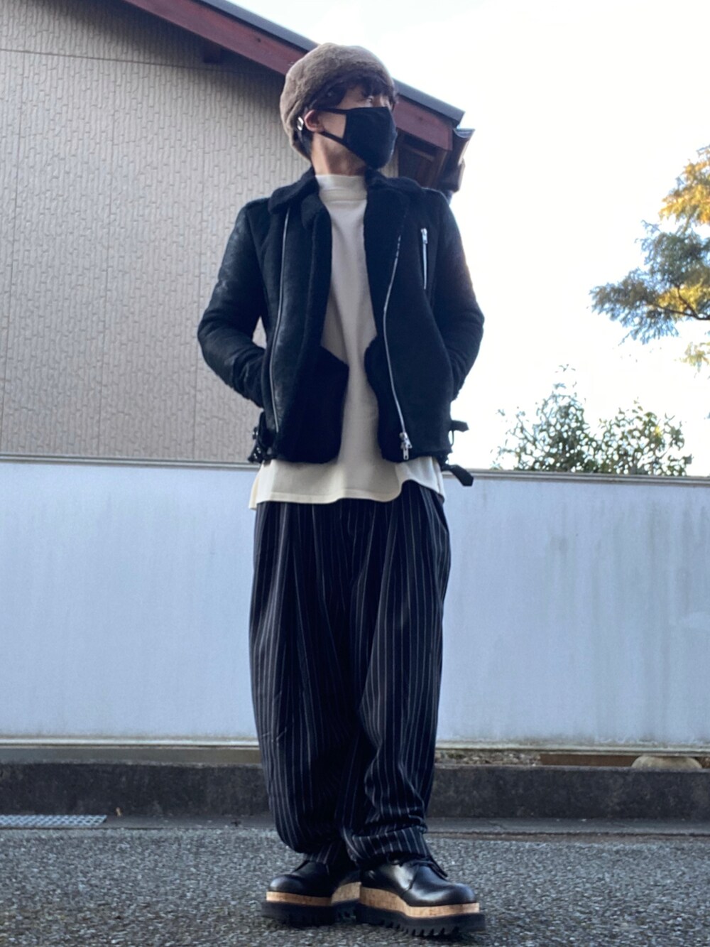 ブラック系のスラックス、ブラック系のムートンコート、ホワイト系のニット/セーターを着用したメンズの冬コーディネートの2枚目の写真