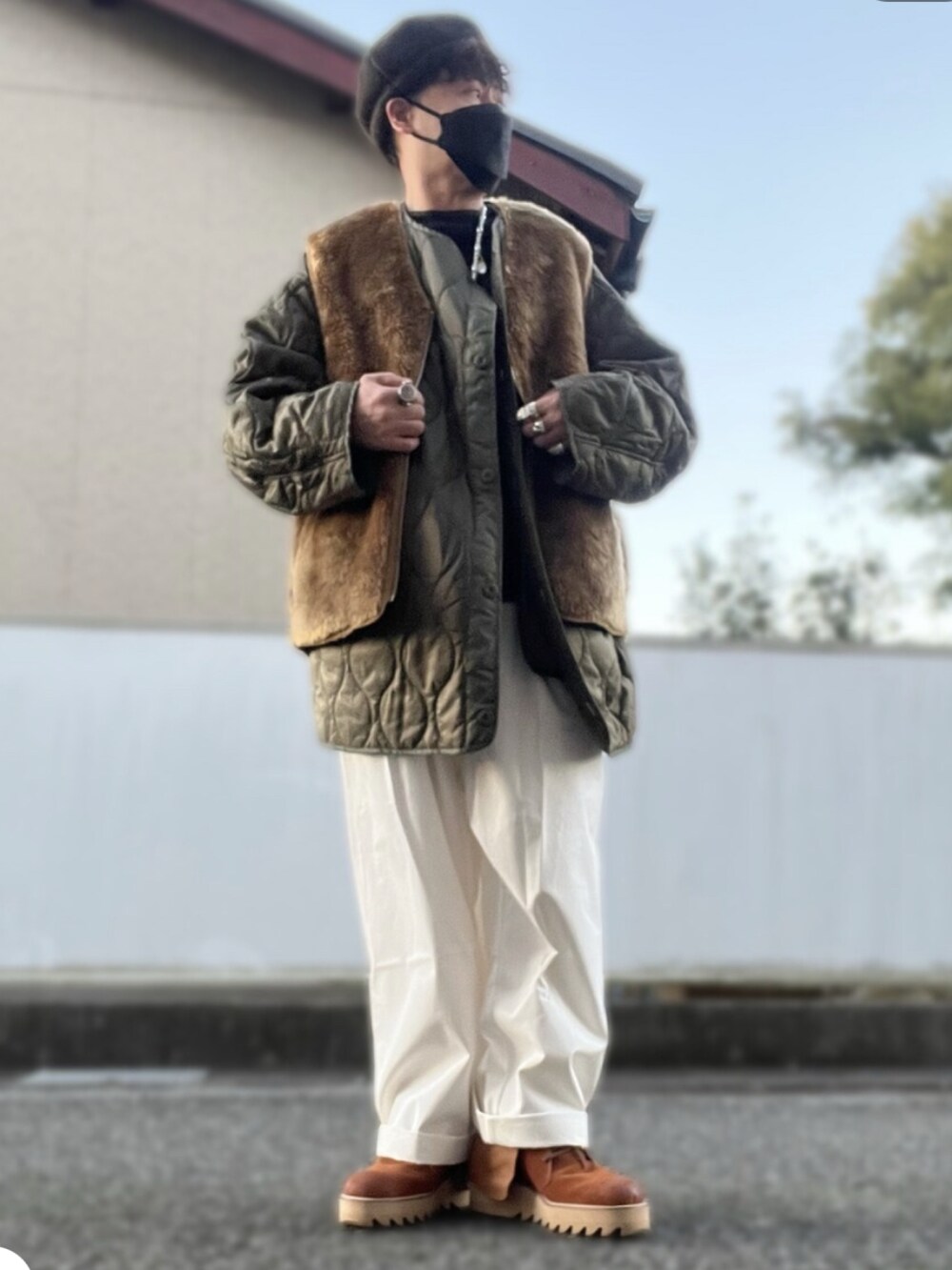 グリーン系のノーカラージャケット、ブラウン系のベスト、ホワイト系のチノパンツを着用したメンズの冬コーディネートの2枚目の写真
