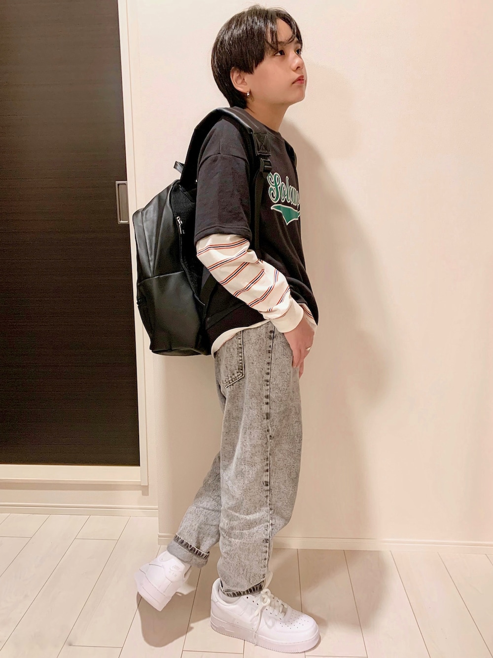 ブラック系のベスト、グレー系のデニムパンツ、ホワイト系のスニーカーを着用したキッズの秋コーディネートの3枚目の写真