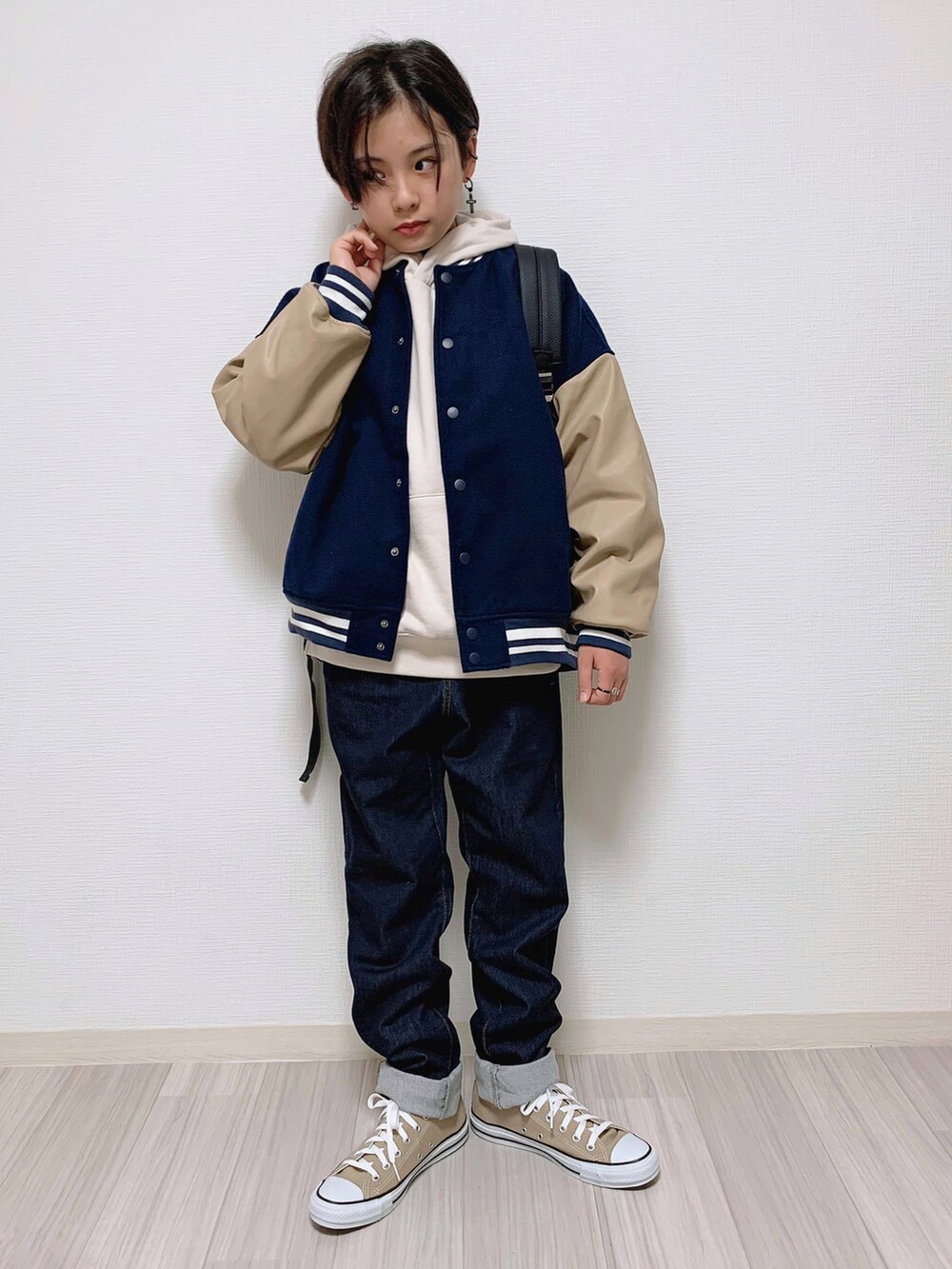 ブルー系のスタジャン、ベージュ系のパーカー、ブルー系のデニムパンツを着用したキッズの冬コーディネートの2枚目の写真