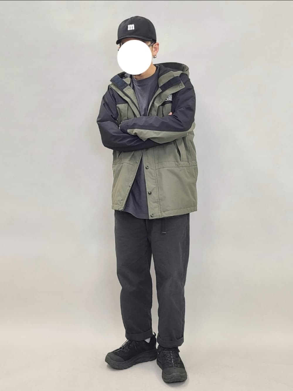 グリーン系のマウンテンパーカー、グレー系のTシャツ/カットソー、ブラック系のパンツを着用したメンズの夏コーディネートの2枚目の写真