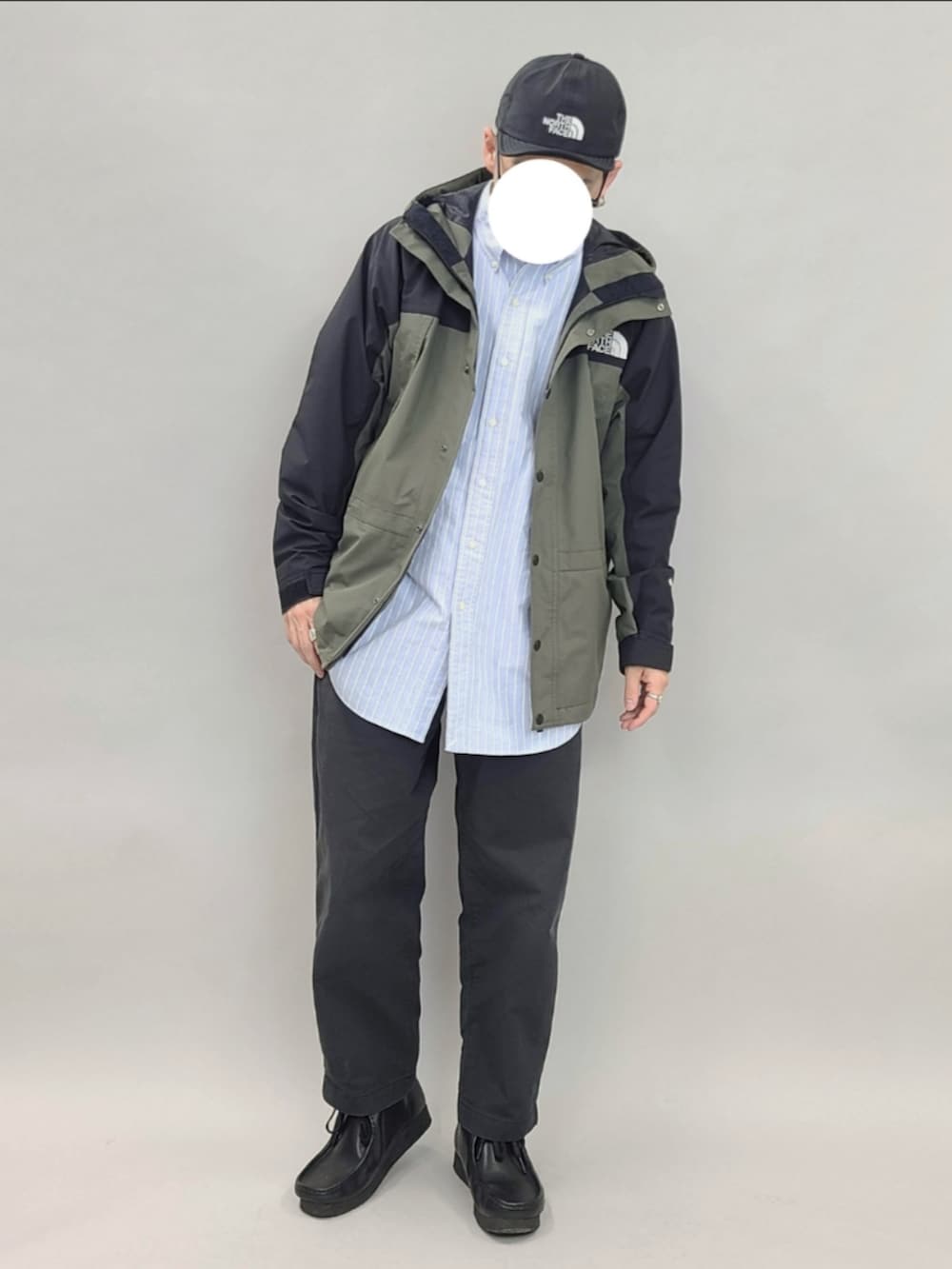 グリーン系のマウンテンパーカー、ブラック系のブーツ、ブラック系のキャップを着用したメンズの春コーディネートの3枚目の写真