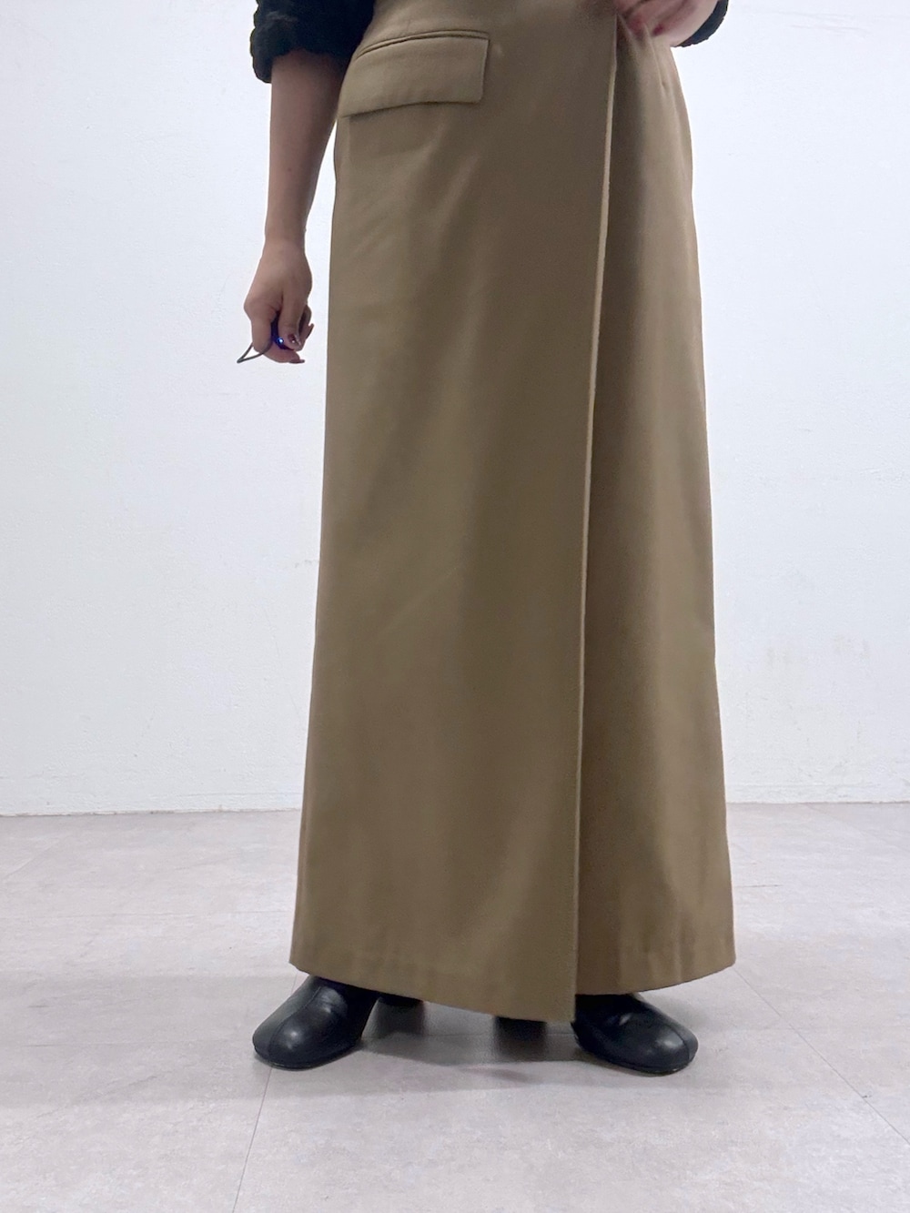 ベージュ系のスカート、ブラック系のシャツ/ブラウス、ブラック系のブーツを着用したレディースの秋コーディネートの3枚目の写真