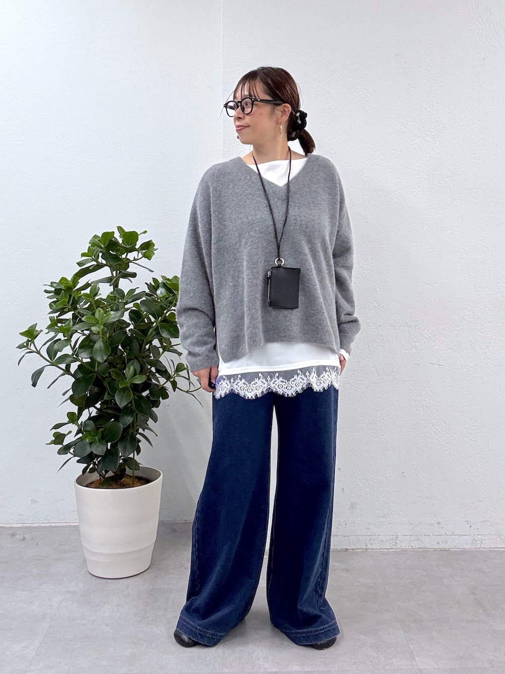 グレー系のニット/セーター、ホワイト系のシャツ/ブラウス、ブルー系のデニムパンツを着用したレディースの秋コーディネートの4枚目の写真