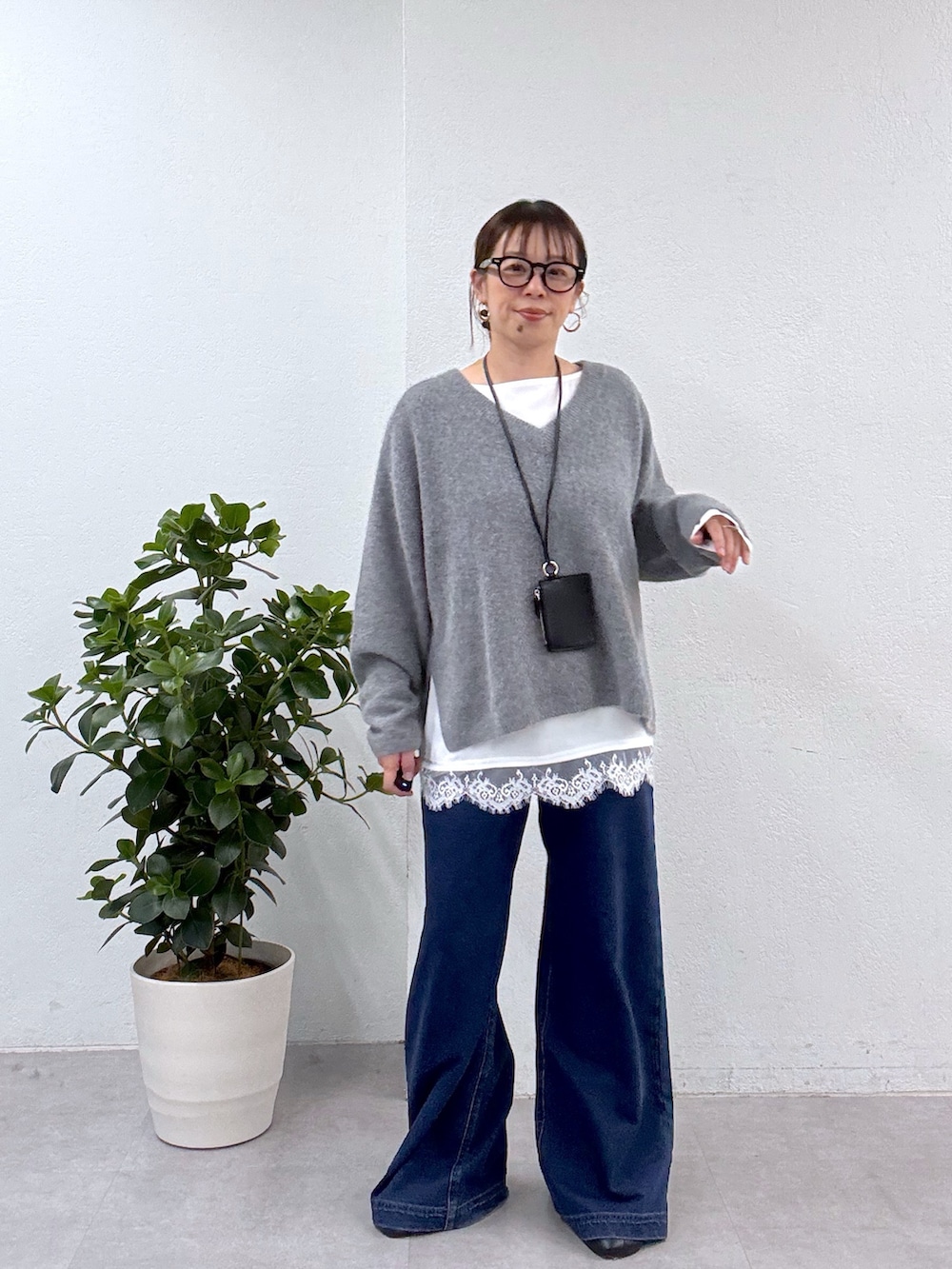 グレー系のニット/セーター、ホワイト系のシャツ/ブラウス、ブルー系のデニムパンツを着用したレディースの秋コーディネートの2枚目の写真