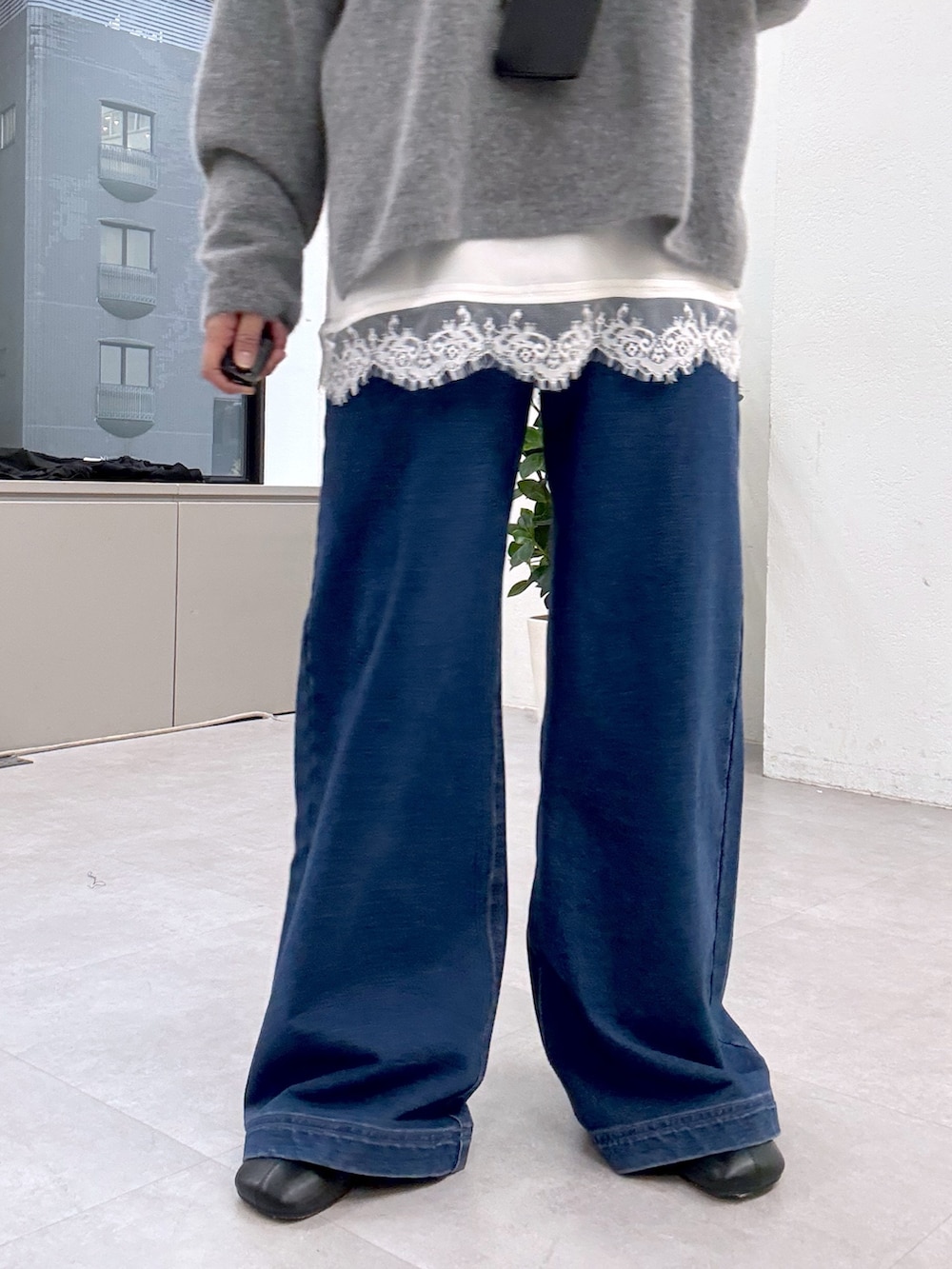 グレー系のニット/セーター、ホワイト系のシャツ/ブラウス、ブルー系のデニムパンツを着用したレディースの秋コーディネートの5枚目の写真