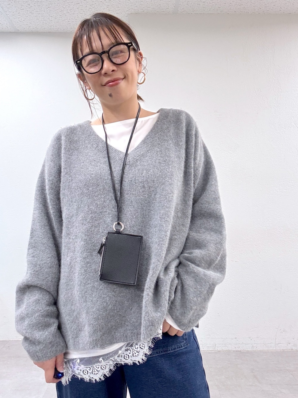 グレー系のニット/セーター、ホワイト系のシャツ/ブラウス、ブルー系のデニムパンツを着用したレディースの秋コーディネートの3枚目の写真