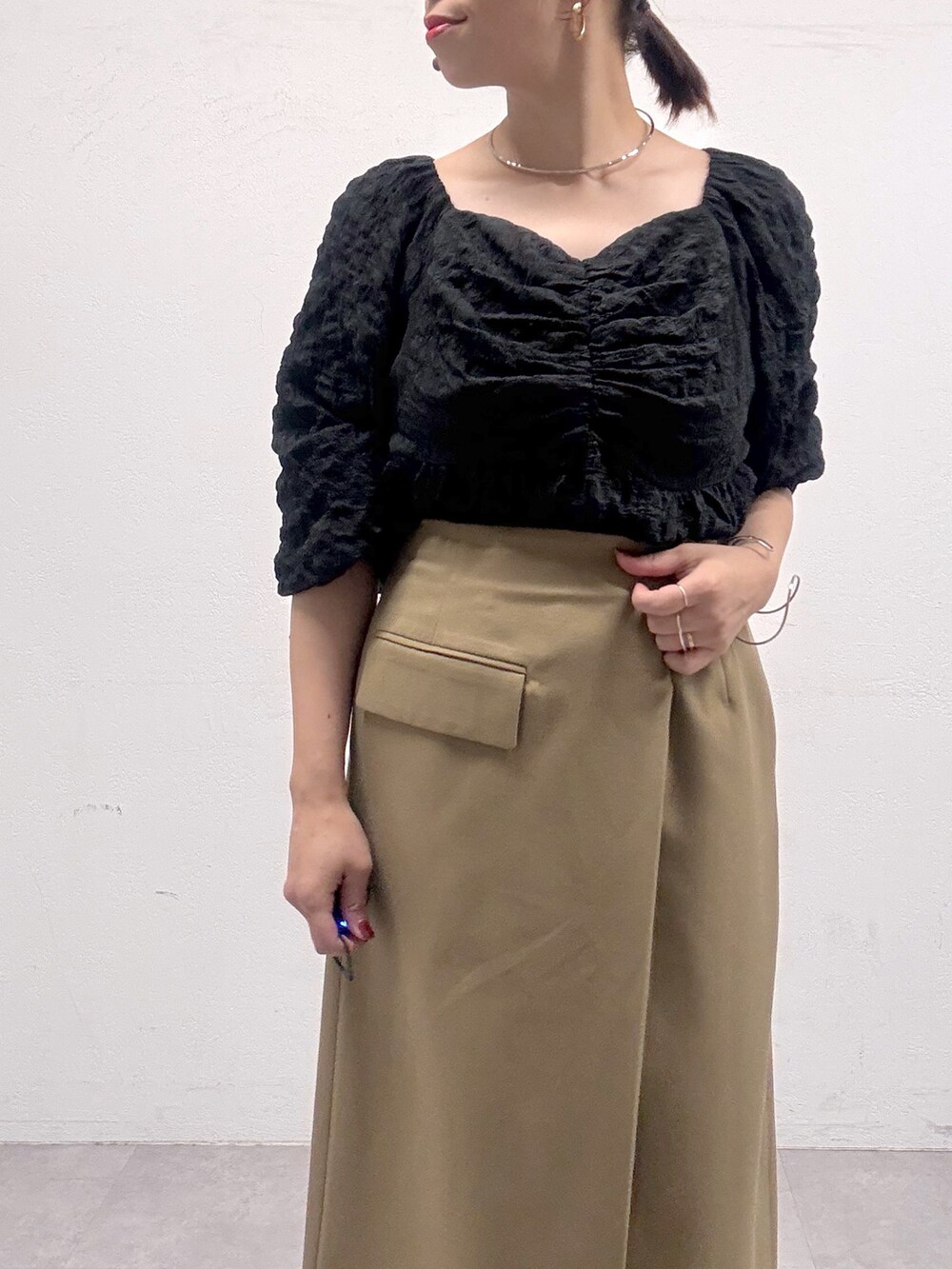 ベージュ系のスカート、ブラック系のシャツ/ブラウス、ブラック系のブーツを着用したレディースの秋コーディネートの5枚目の写真