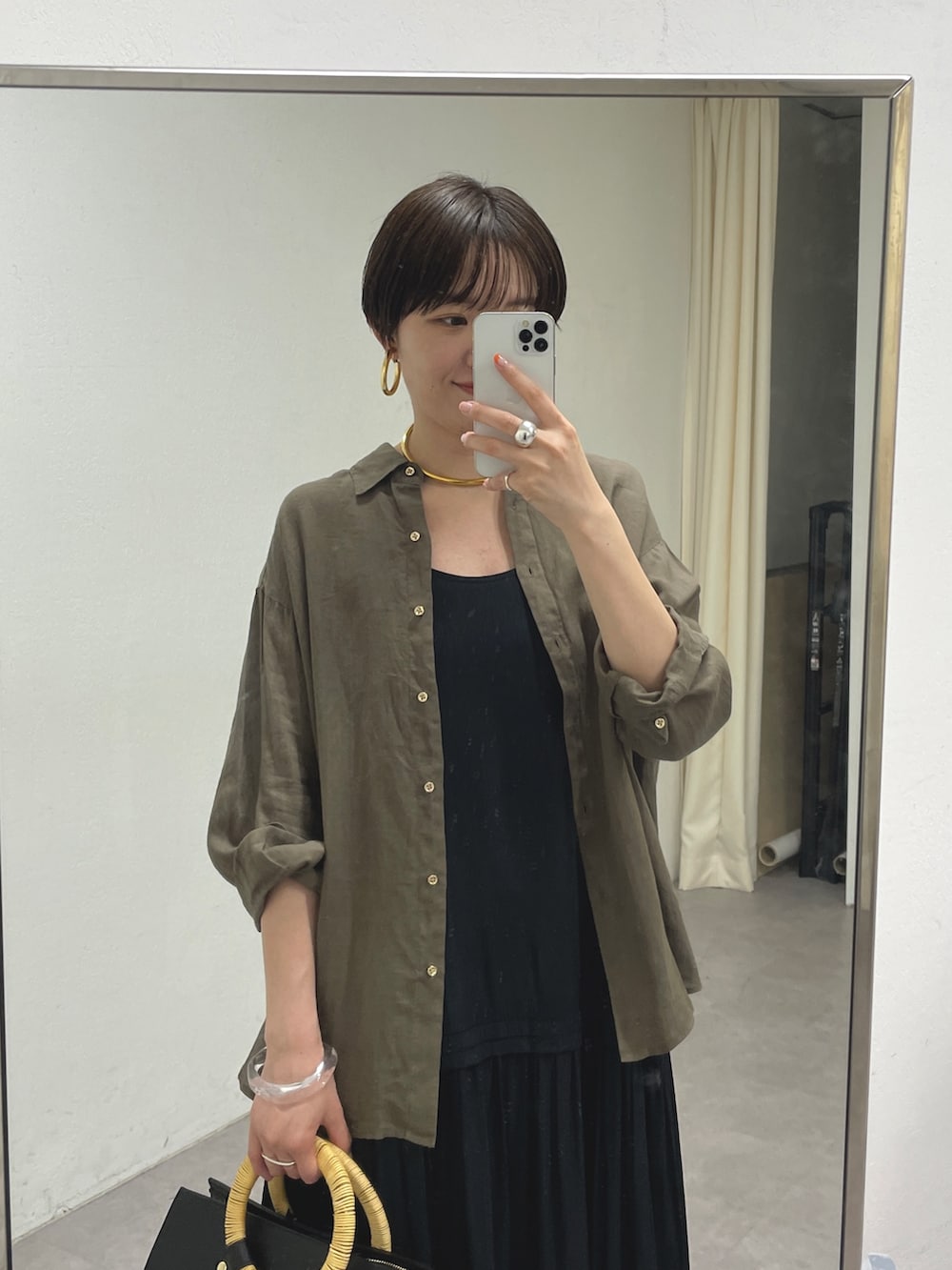 ゴールド系のブーツ、グリーン系のシャツ/ブラウス、ブラック系のワンピースを着用したレディースの春コーディネートの2枚目の写真