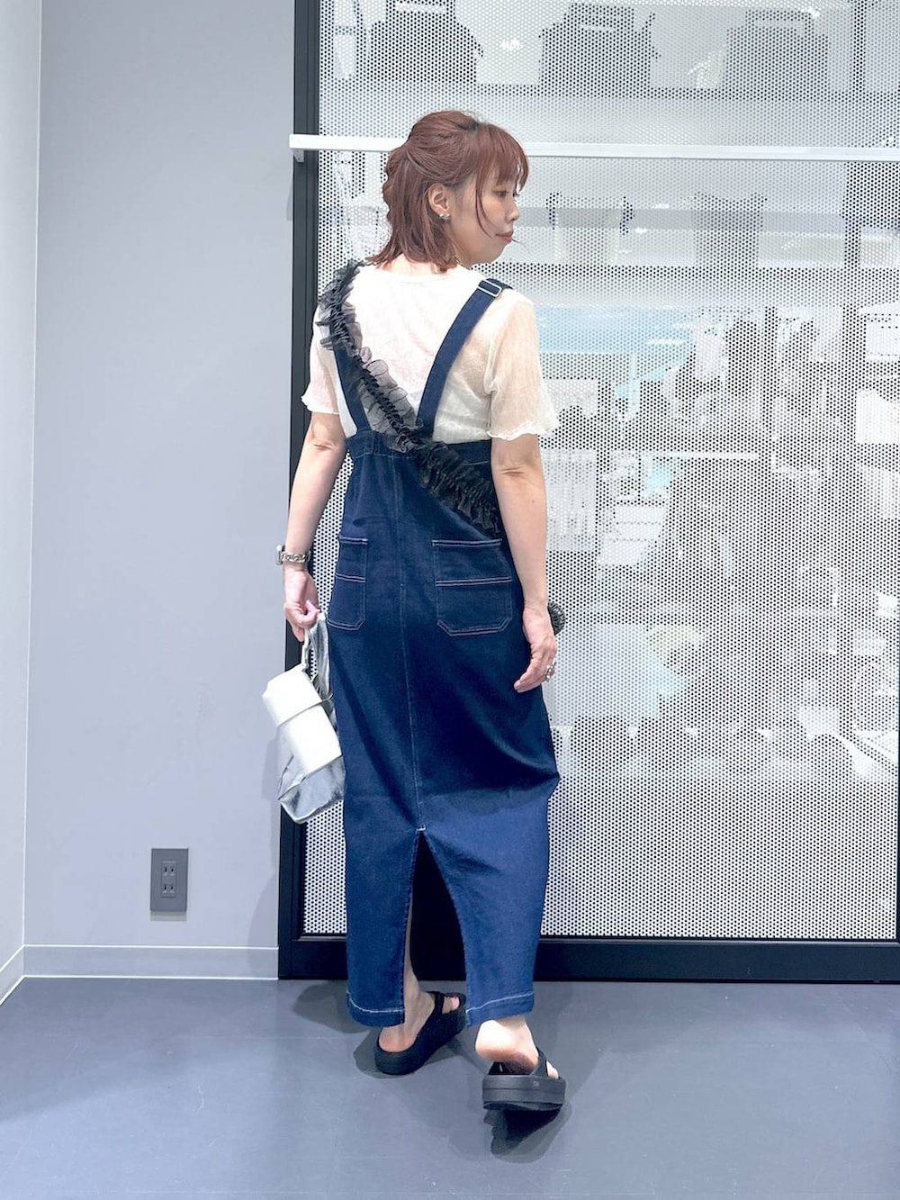 ブルー系のジャンパースカート、ブラック系のサンダル、ベージュ系のTシャツ/カットソーを着用したレディースの夏コーディネートの3枚目の写真