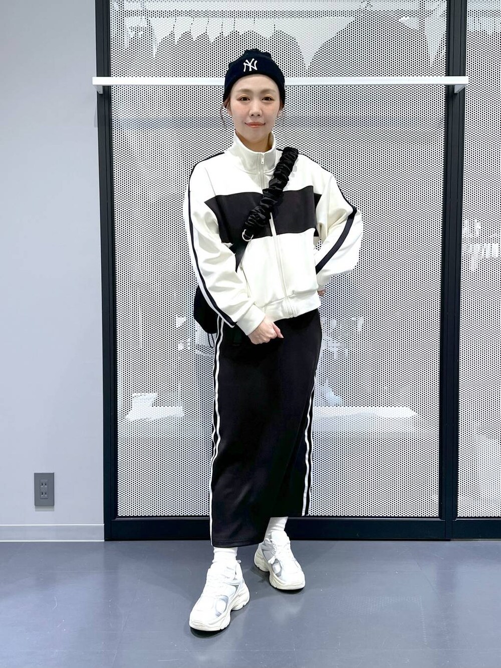 ブラック系のスカート、ベージュ系のブルゾン、ホワイト系のスニーカーを着用したレディースの冬コーディネートの2枚目の写真